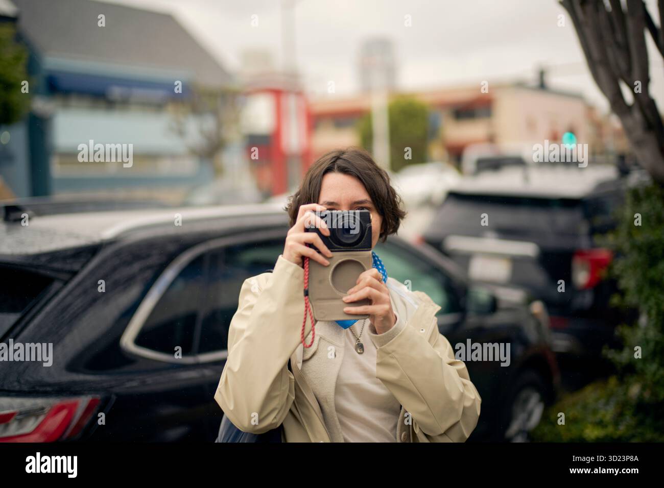 Femme en veste blanche prenant une photo avec un appareil photo dans une rue de la ville. Californie, États-Unis Banque D'Images