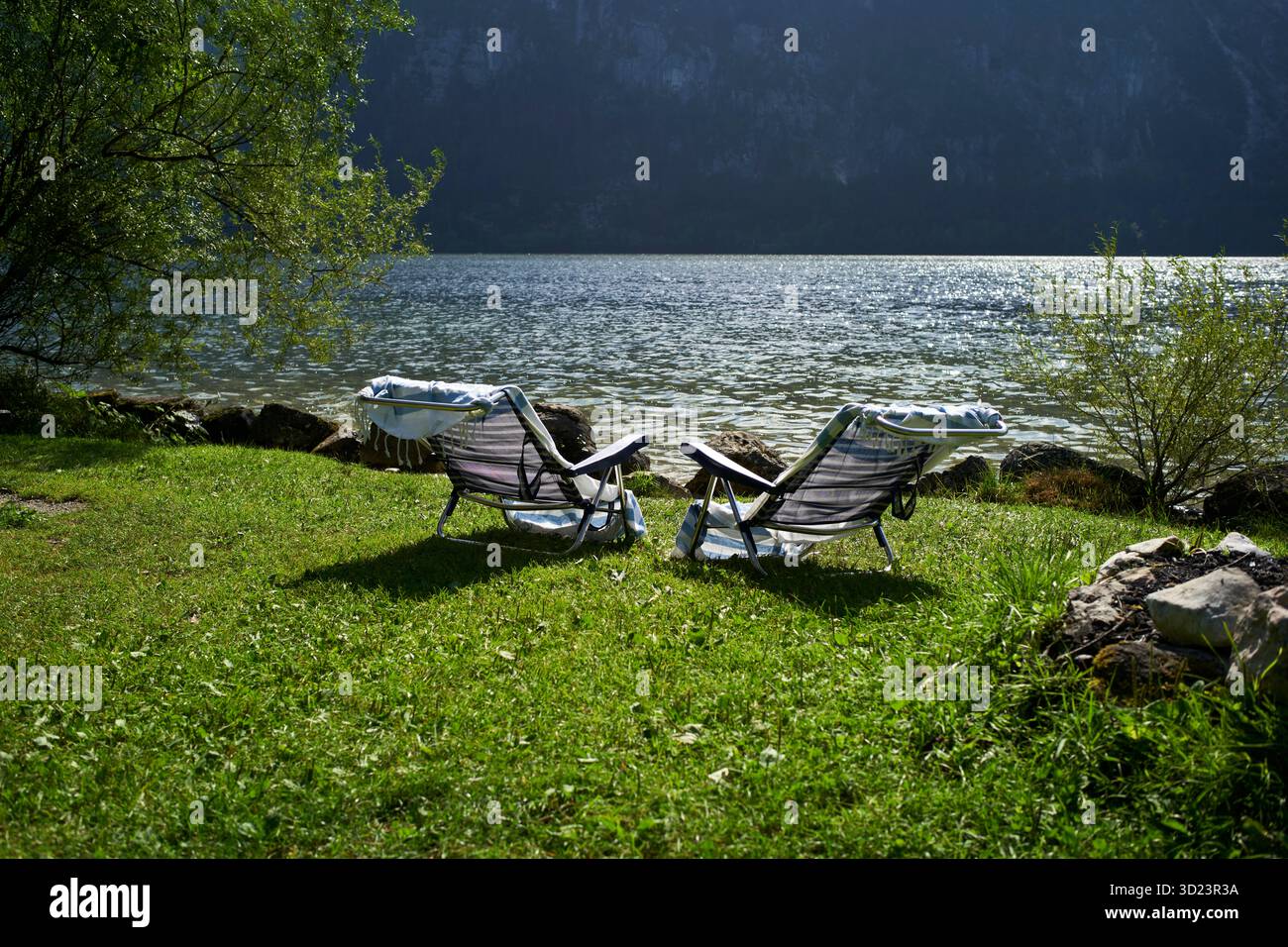 Deux chaises longues sur le bord d'un lac herbeux avec l'eau calme et la montagne en toile de fond. Salzkammergut, domaine salin, montagnes de Dachstein, Autriche Banque D'Images