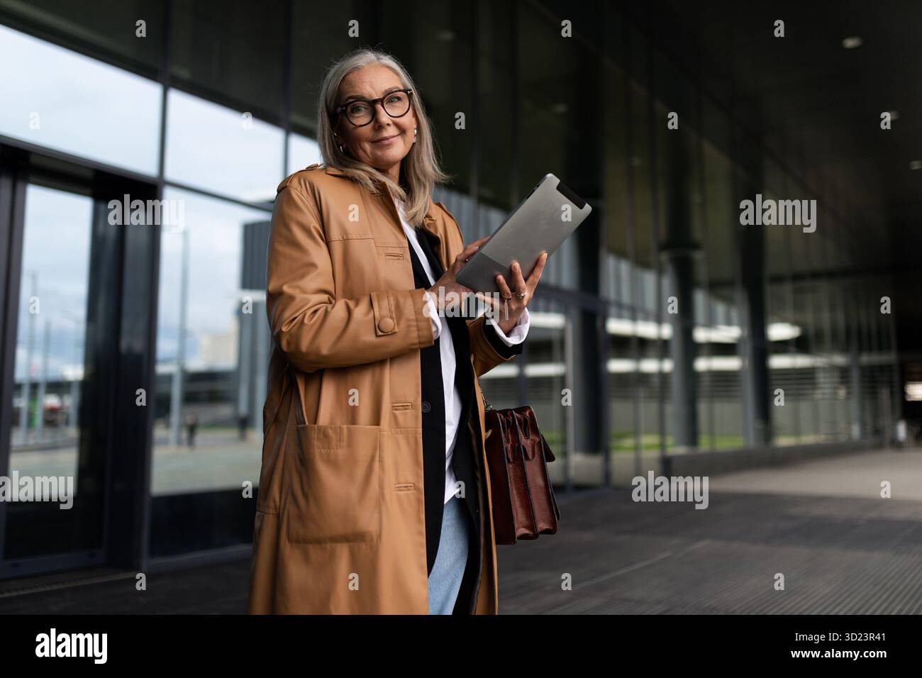 Femme âgée élégante avec une tablette dans ses mains sur le fond du centre commercial Banque D'Images