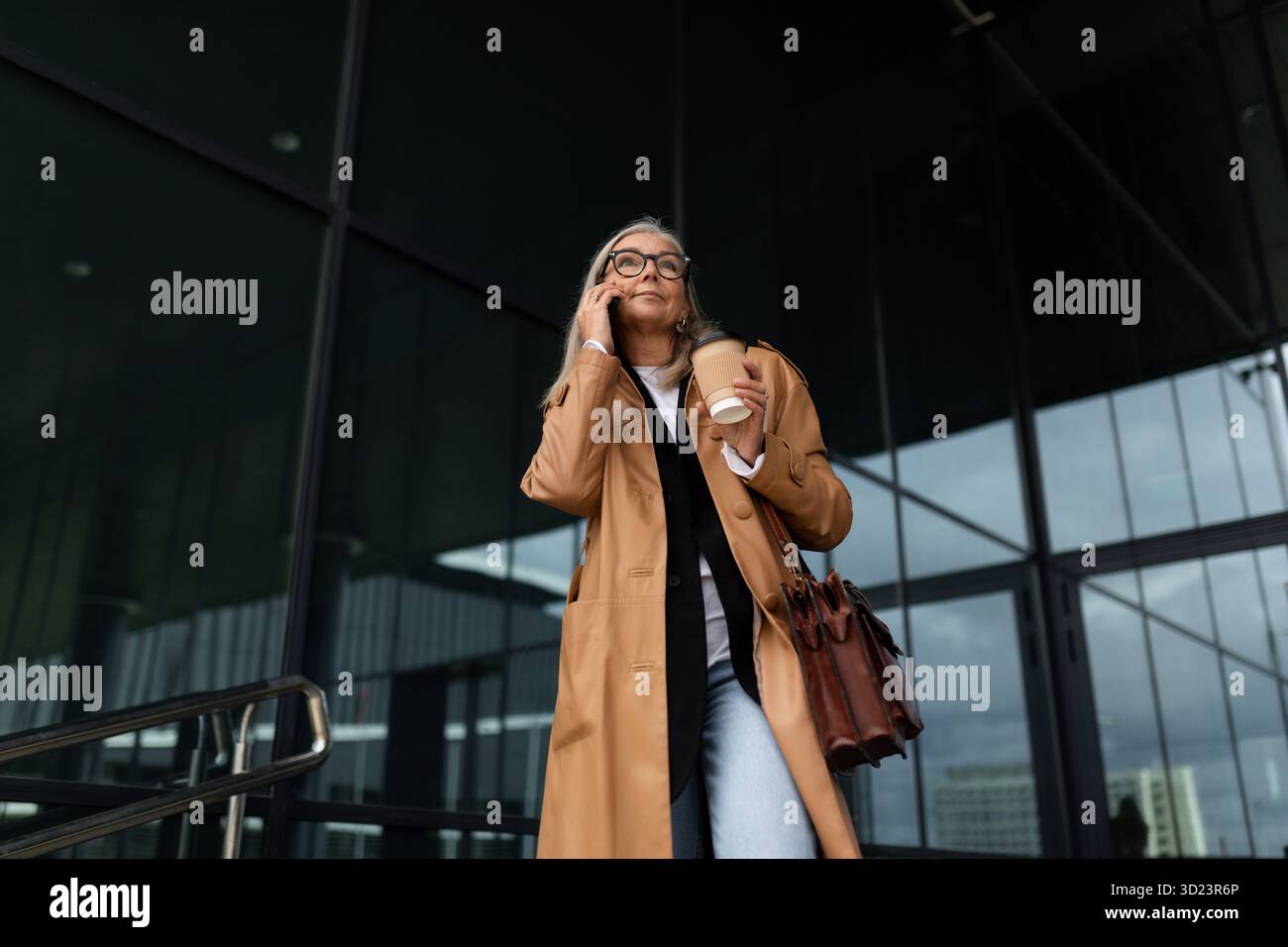 Femme âgée femme d'affaires quittant le bureau parlant sur un téléphone portable Banque D'Images