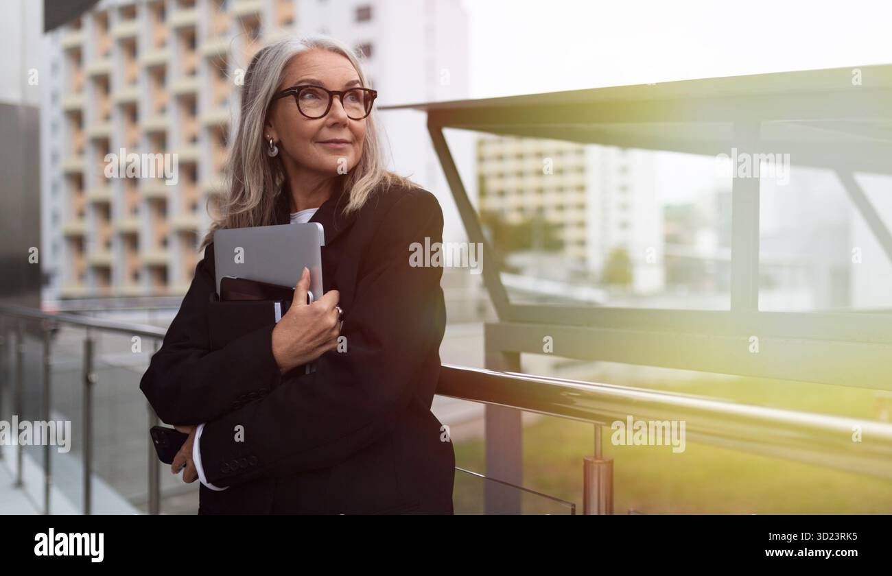 Femme d'affaires âgée avec un ordinateur portable dans ses mains sur fond de centre de bureau Banque D'Images