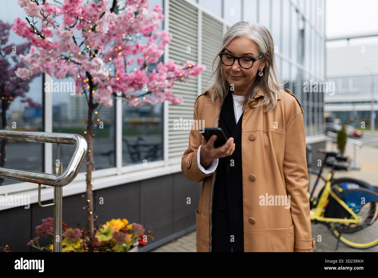 Femme âgée élégante avec un téléphone portable dans ses mains dans la ville Banque D'Images