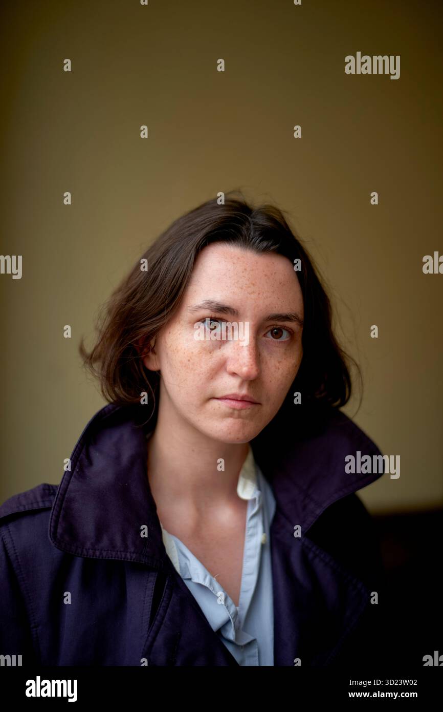 Jeune femme avec les cheveux bruns courts dans le manteau violet regarde dans la caméra dans le couloir sombre. Bruxelles, Belgique Banque D'Images