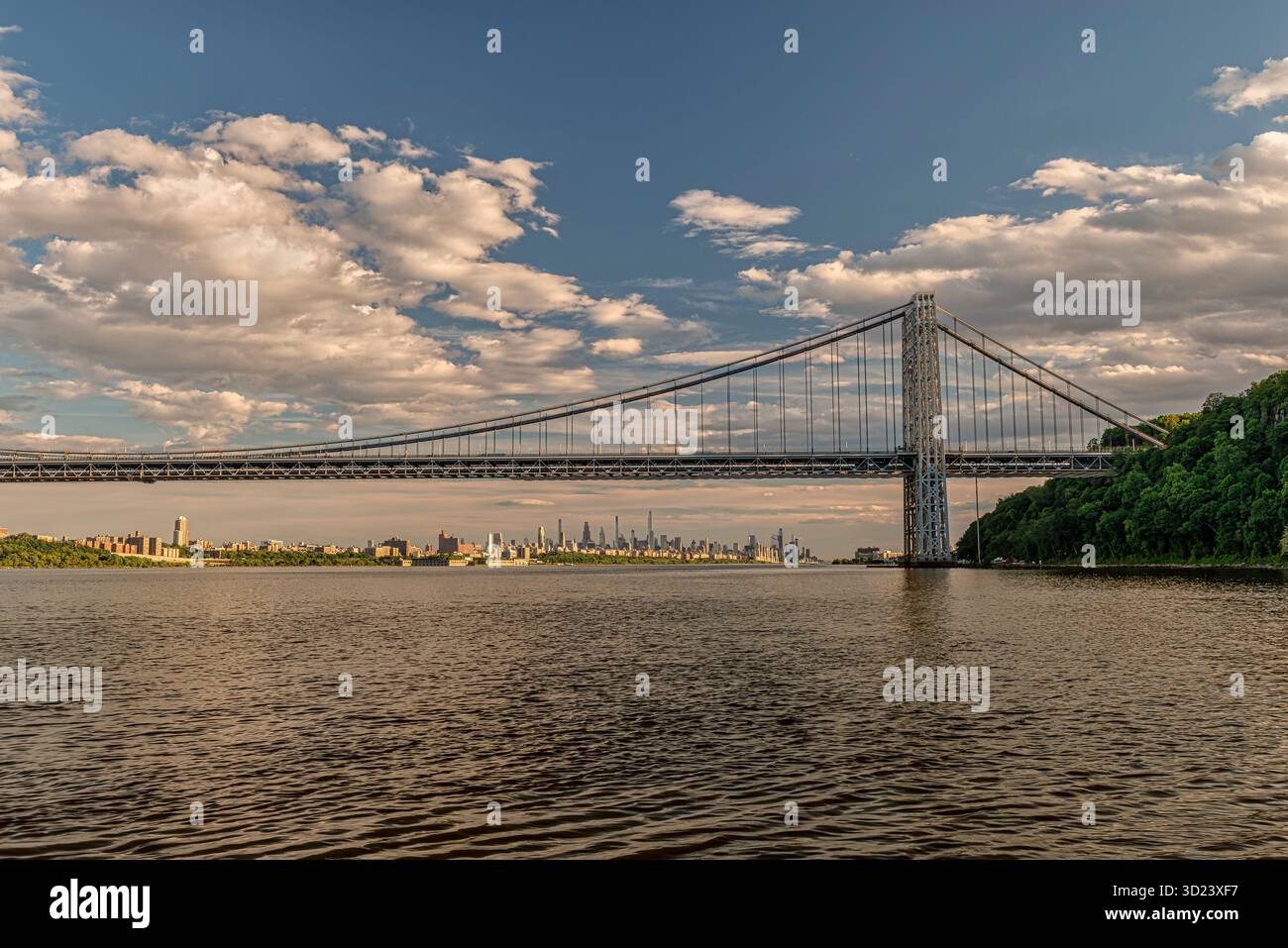 Pont suspendu au-dessus d'une large rivière avec une ligne d'horizon de la ville, des arbres, et un ciel nuageux. New York City, NY, États-Unis George Washington Bridge, Hudson River Banque D'Images