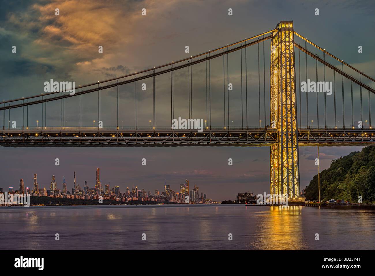 Pont illuminé au coucher du soleil sur une rivière calme avec une ligne d'horizon de la ville au loin. New York City, NY, États-Unis George Washington Bridge, Hudson River Banque D'Images