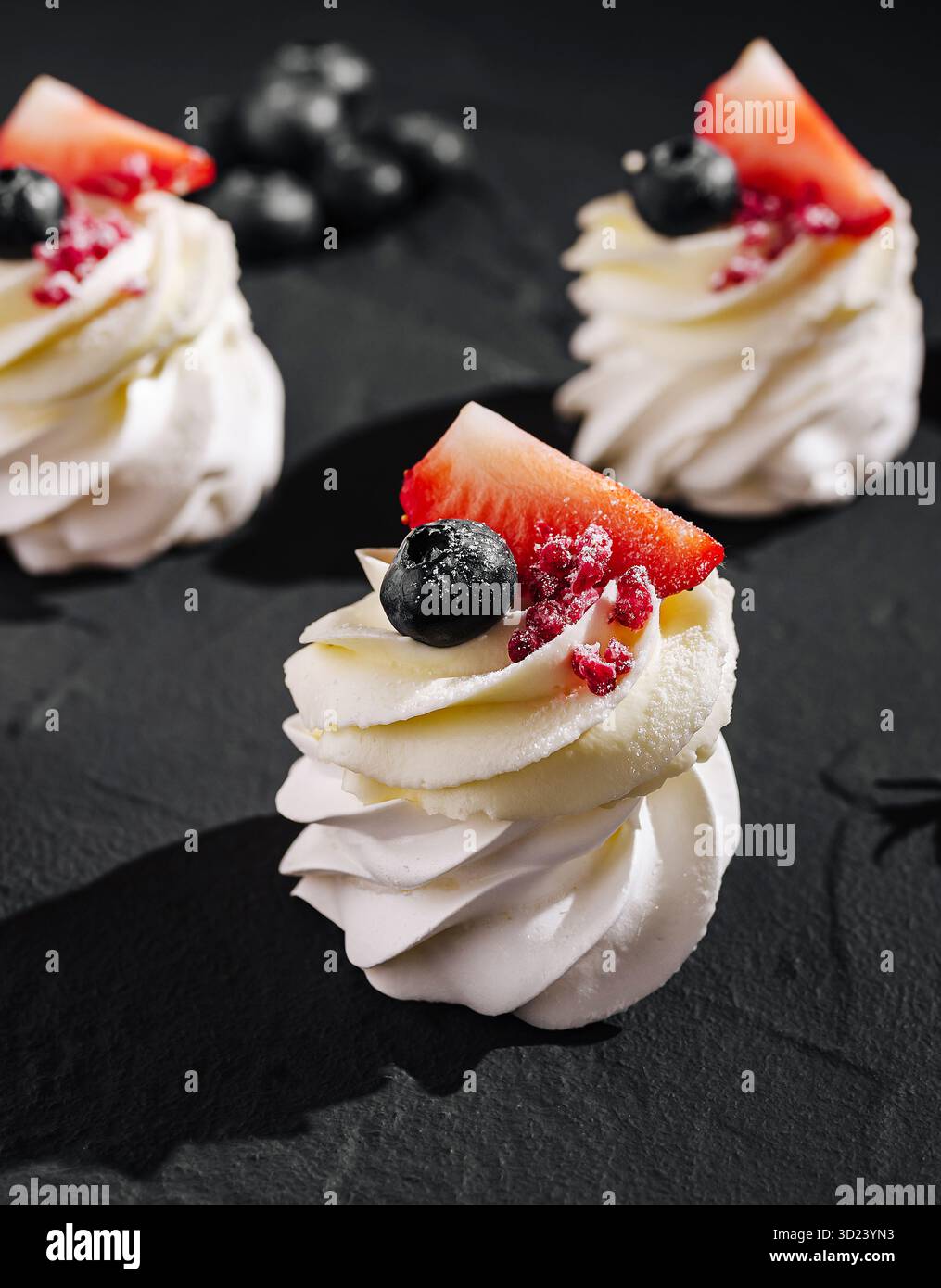 Délicieux desserts meringués recouverts de fruits frais sur fond sombre Banque D'Images