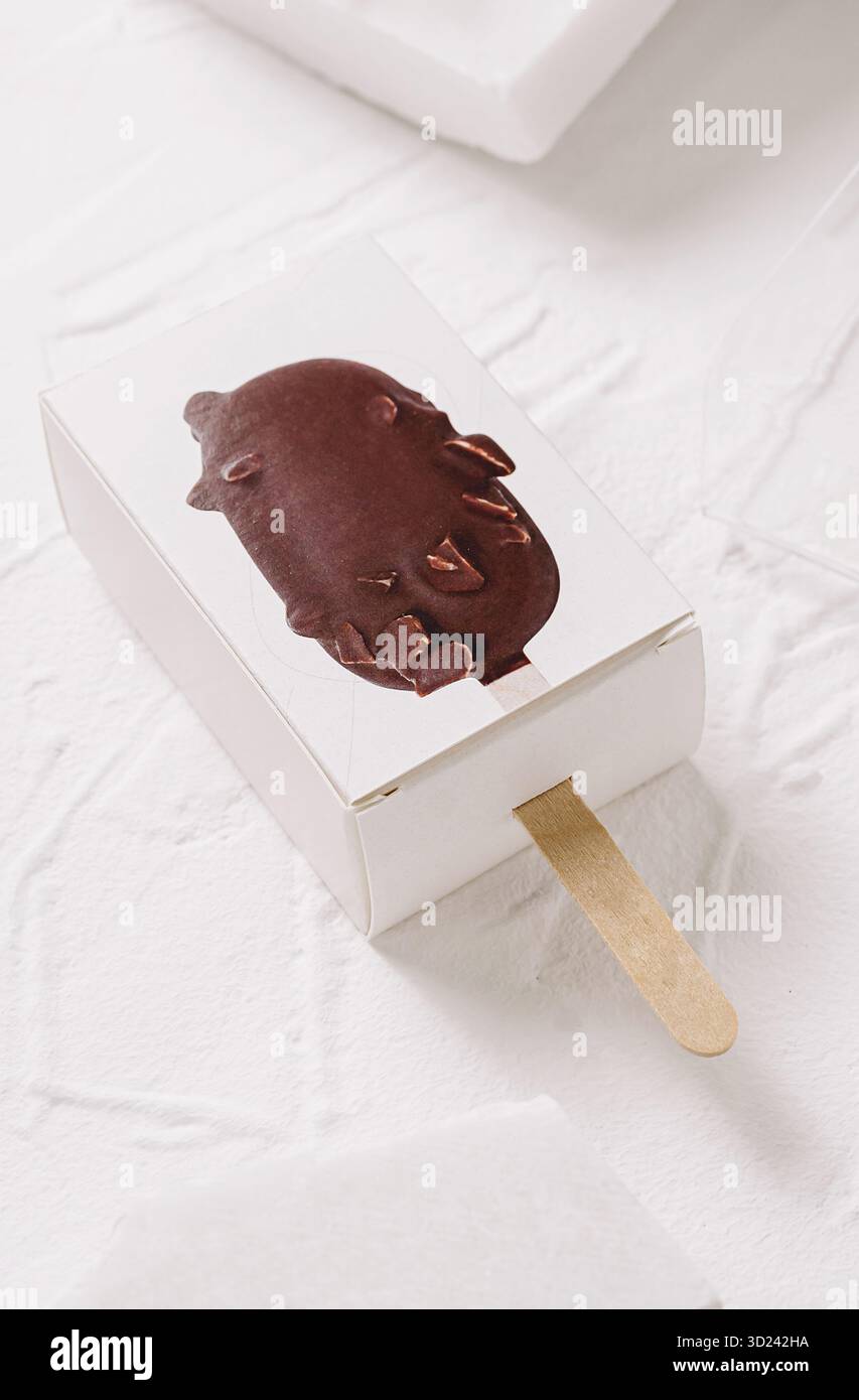 Délicieuse barre de crème glacée recouverte de chocolat dans un emballage simple sur une surface Banque D'Images