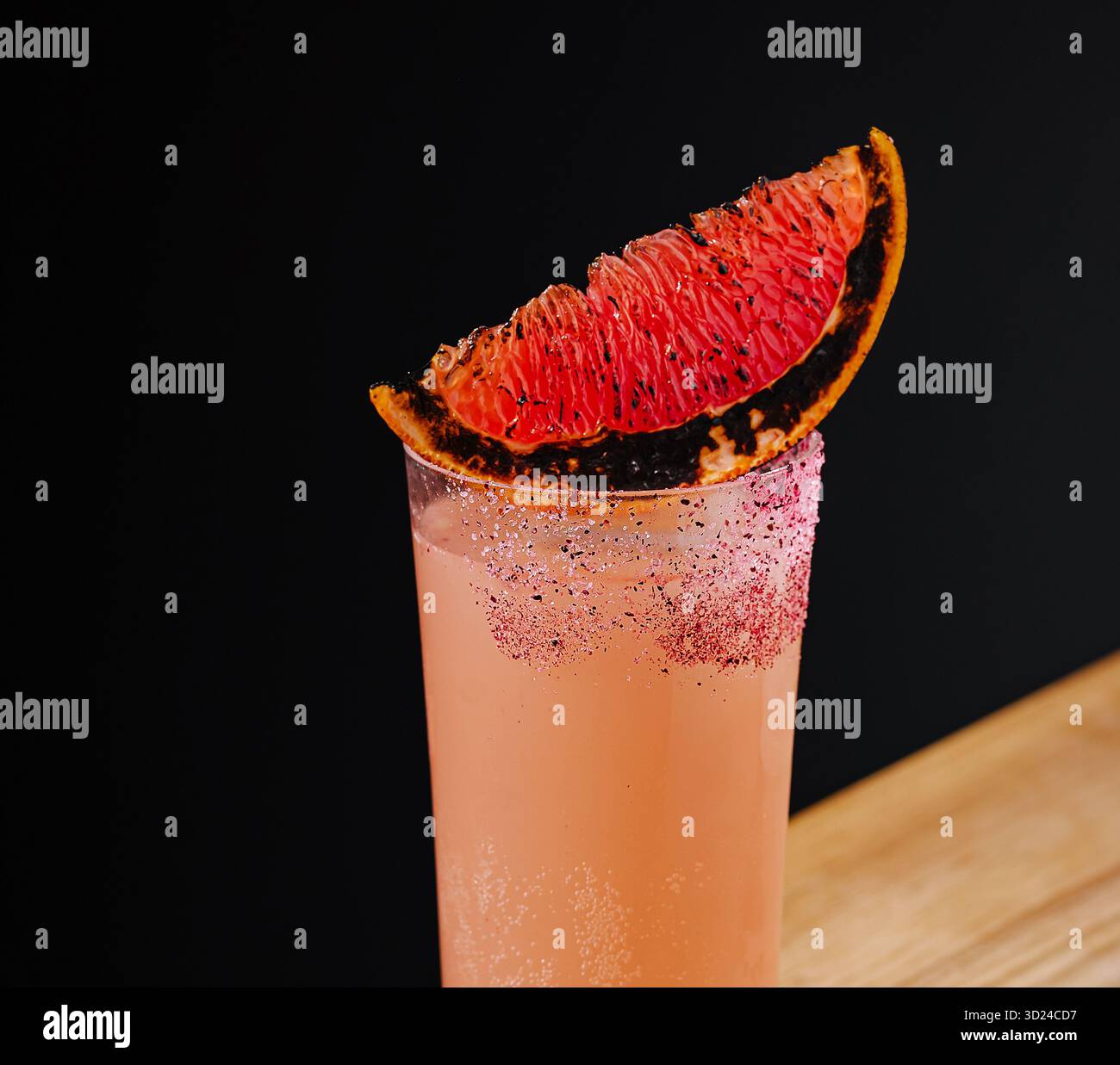 Cocktail vibrant avec des agrumes carbonisés sur une surface en bois sur fond sombre Banque D'Images
