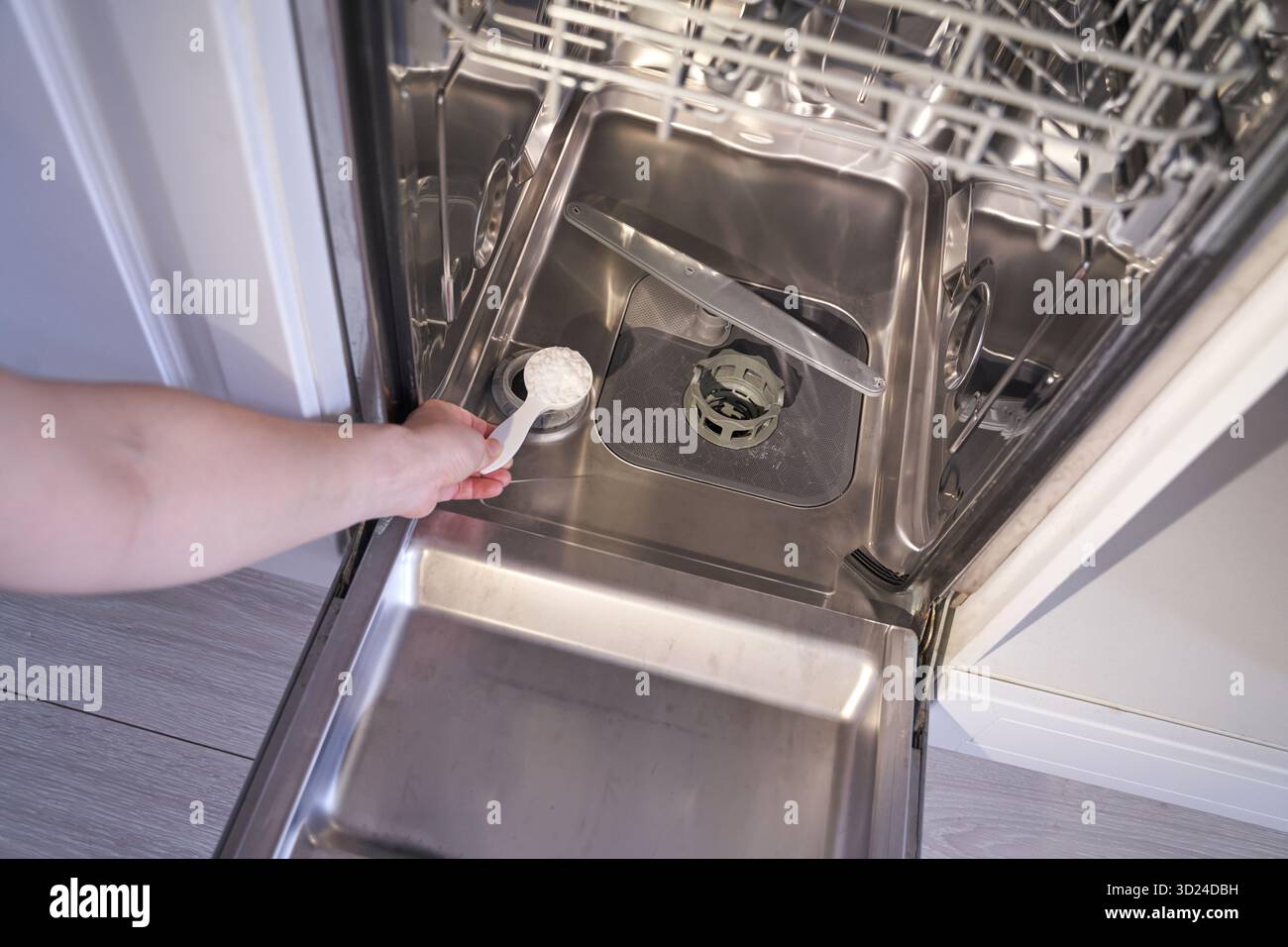 Personne chargeant le lave-vaisselle avec du détergent dans un appareil de cuisine ouvert Banque D'Images