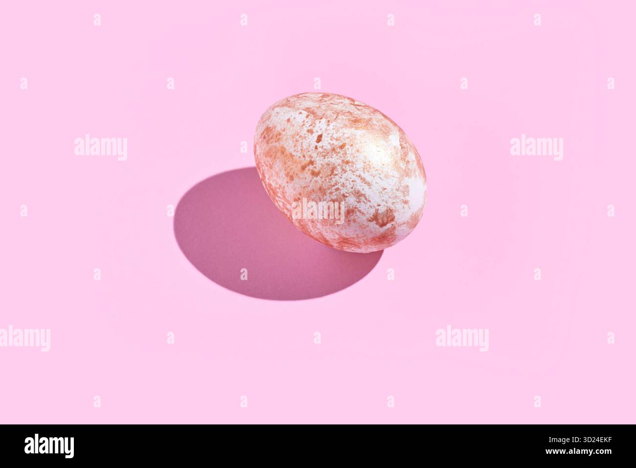 Oeuf moucheté avec ombre sur fond rose composition minimaliste Banque D'Images