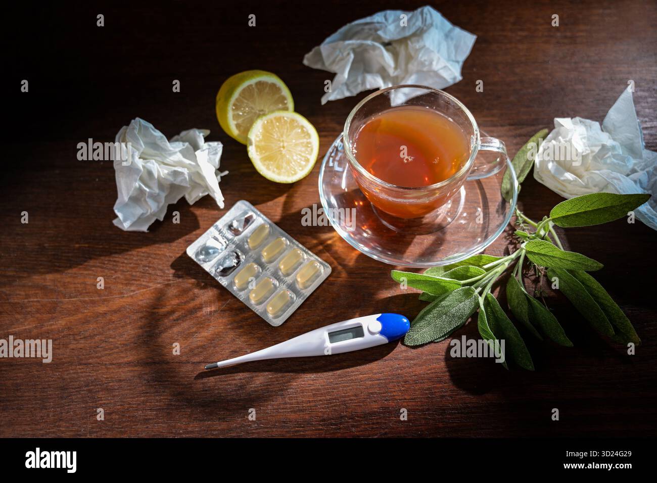 Traitements en saison du rhume et de la grippe, tisane, sauge, citron, pilules, thermomètre et quelques tissus utilisés sur une table en bois, focus sélectionné Banque D'Images