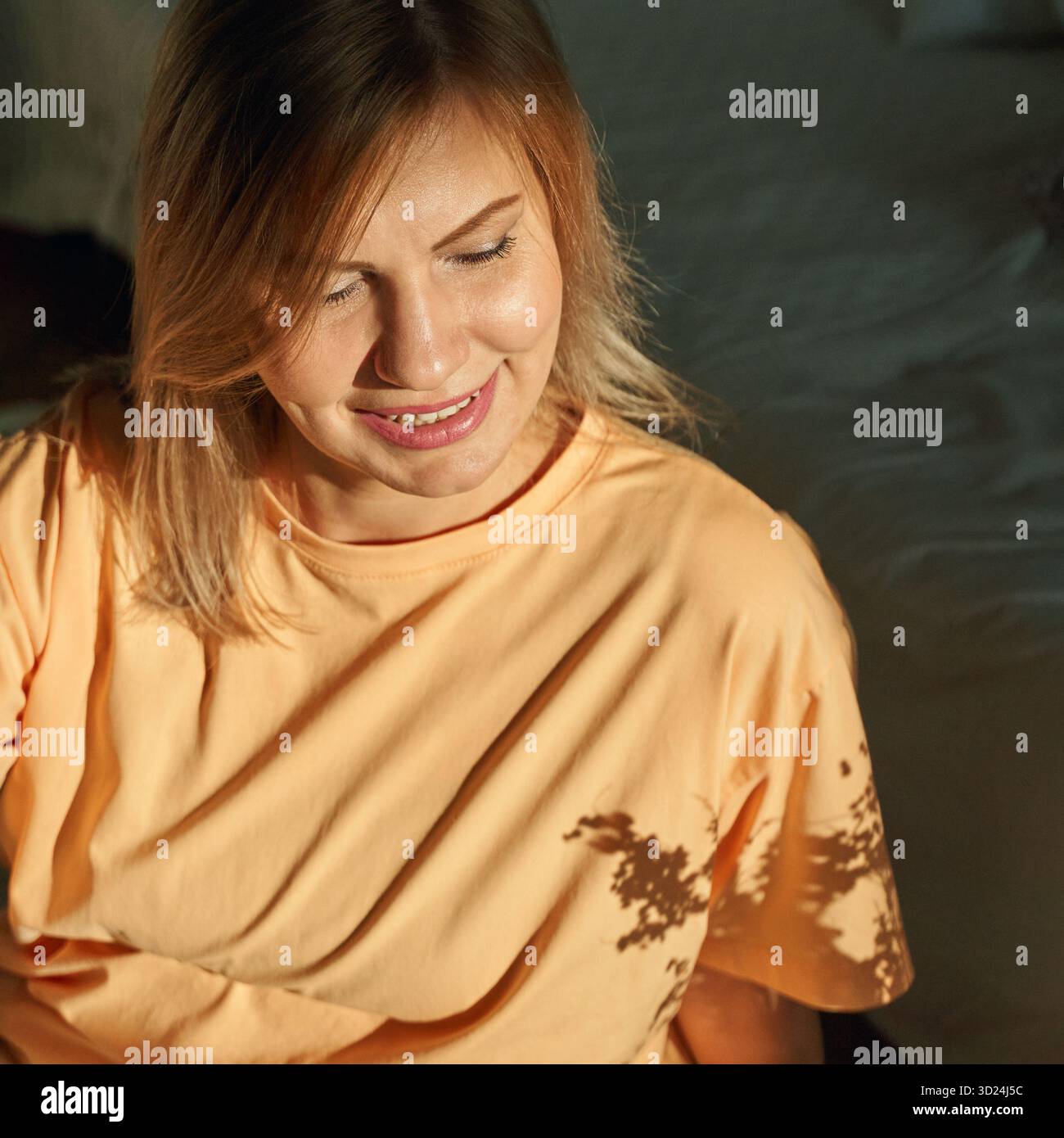 Jeune femme caucasienne se relaxant à l'intérieur avec la lumière du soleil projetant des ombres dans une ambiance décontractée Banque D'Images