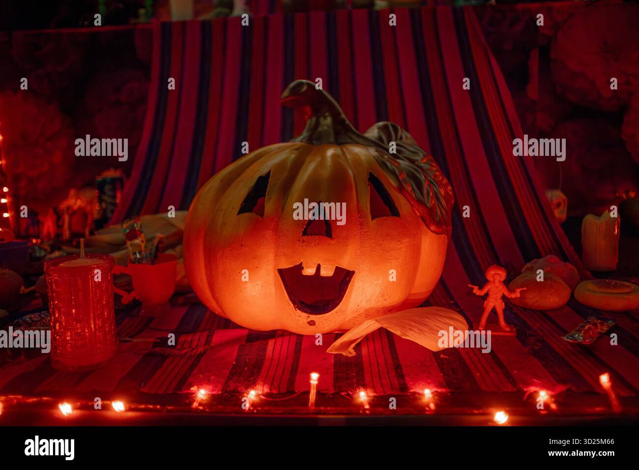 Citrouille d'Halloween sculptée classique brillante dans un cadre sombre et festif avec des jeux de lumières et une décoration saisonnière. Banque D'Images