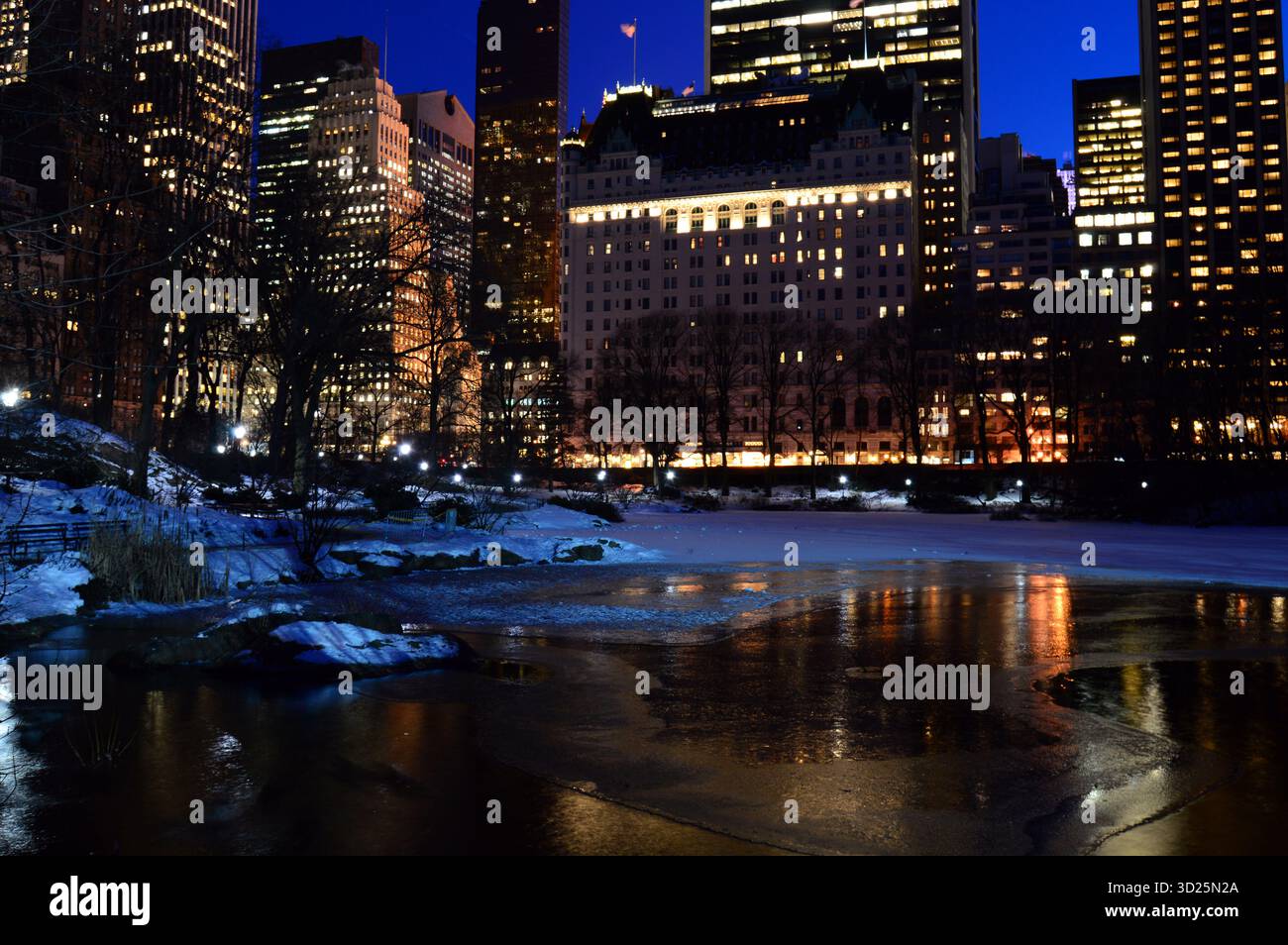 Les lumières du Plaza Hotel et de la skyline de New York se reflètent dans l'eau gelée de l'étang de Central Park Banque D'Images