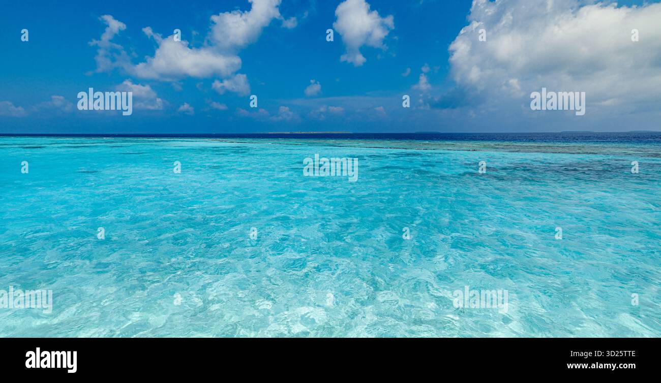 Océan turquoise calme, récif corallien dans une eau peu profonde, ciel bleu panorama. Paysage marin tropical. Fond de papier peint pour voyages en vacances d'été, paradis Banque D'Images