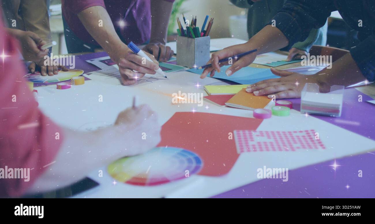 Équipe collaboratrice dessinant et arrangeant au studio de design, avec découpes en papier et roue chromatique Banque D'Images