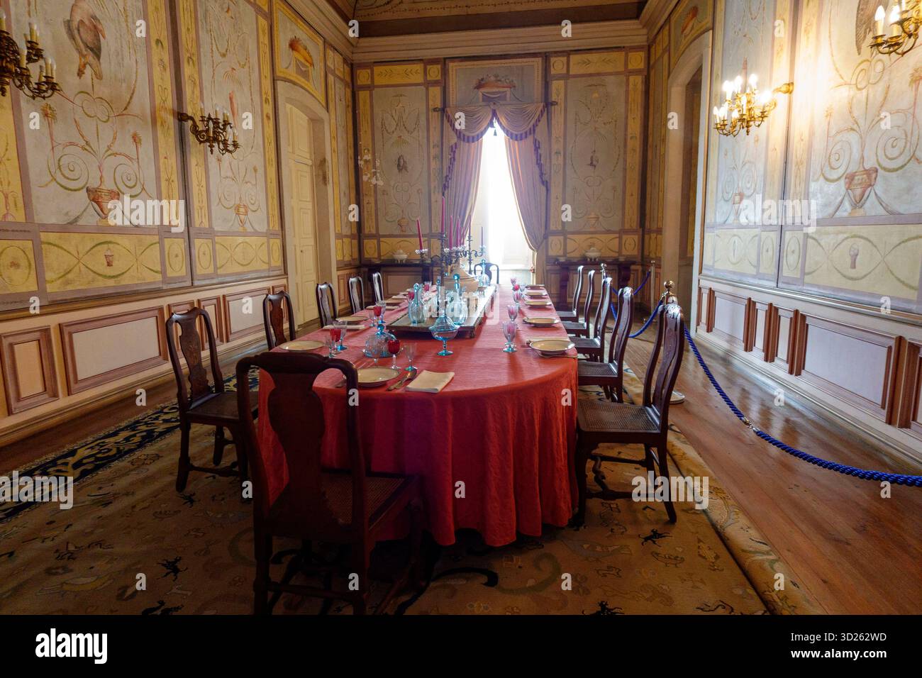 Élégante salle à manger historique avec une table ronde rouge, des chaises en bois et des décorations murales ornées à l'intérieur d'un bâtiment du patrimoine Banque D'Images