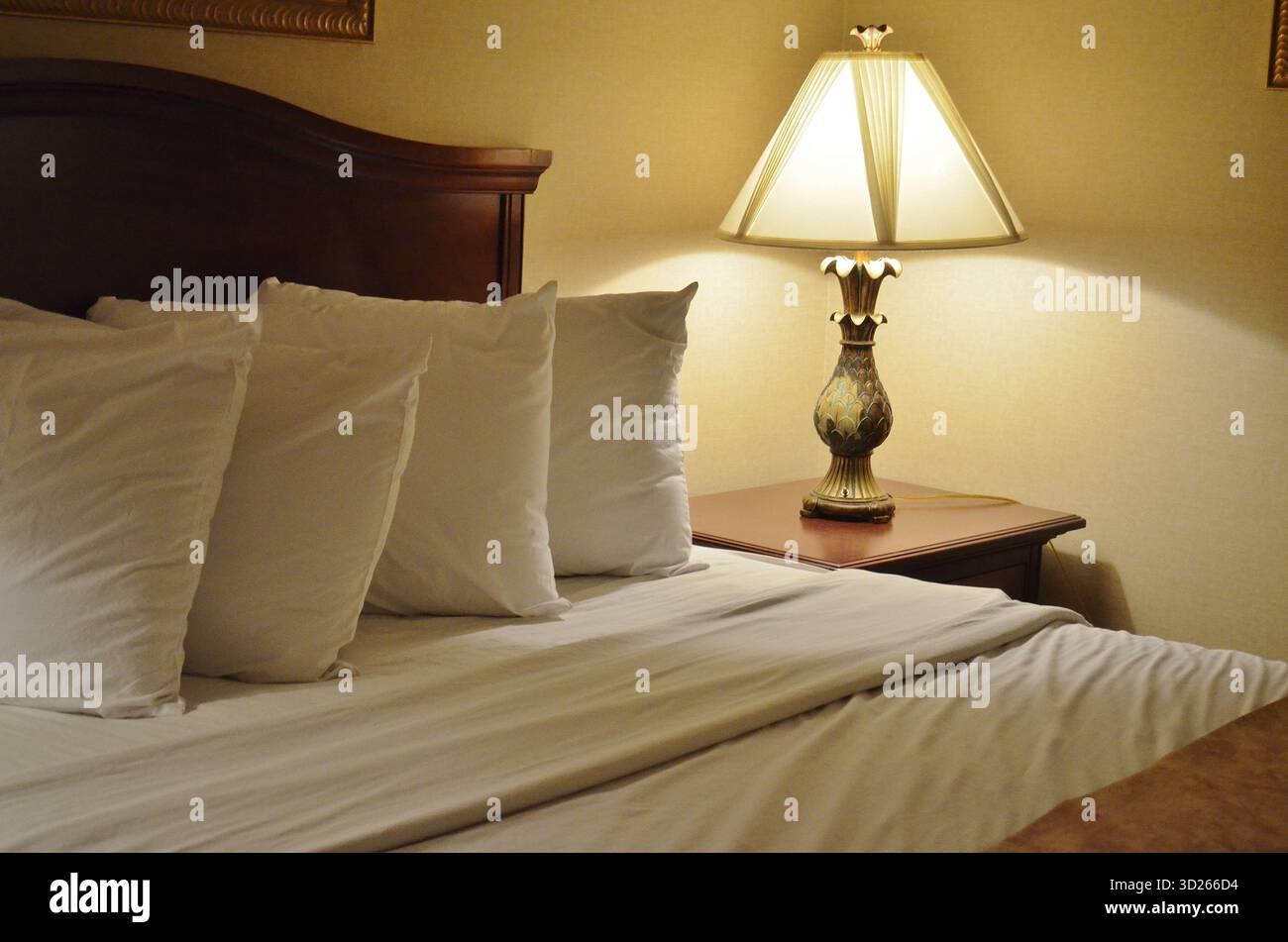 Grand lit confortable avec quatre oreillers et draps blancs propres pour des nuits agréables de sommeil réparateur lors d'un long voyage d'affaires. Banque D'Images