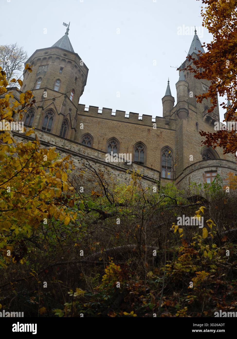 Château de Hohenzollern tours et tourelles encadrées par des feuilles d'automne contre ciel nuageux à Burg Hohenzollern Allemagne 10/22/2025 Banque D'Images