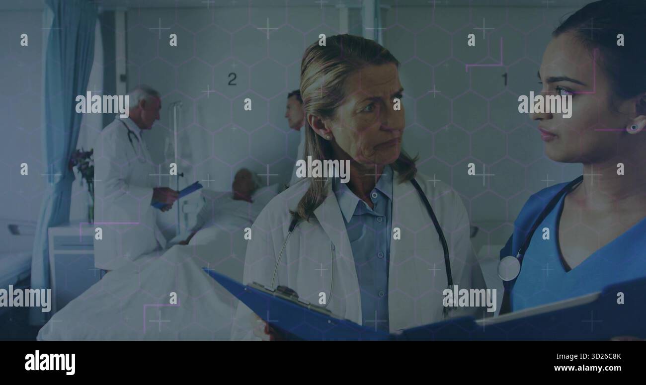 Médecin senior en blouse de laboratoire discutant des dossiers de patient dans la chambre d'hôpital, avec presse-papiers, stéthoscope Banque D'Images