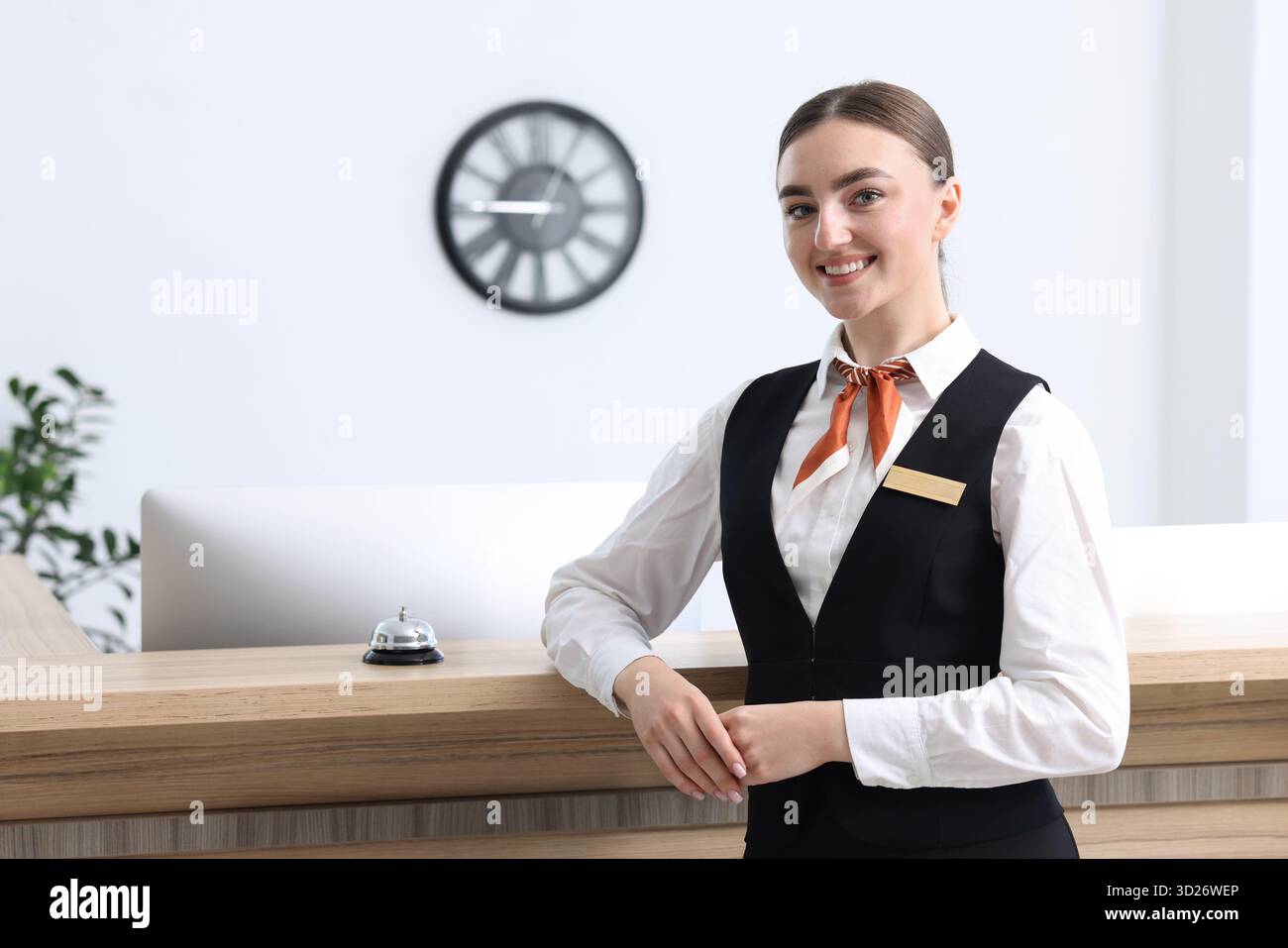 Heureux réceptionniste en uniforme près de la réception à l'intérieur Banque D'Images