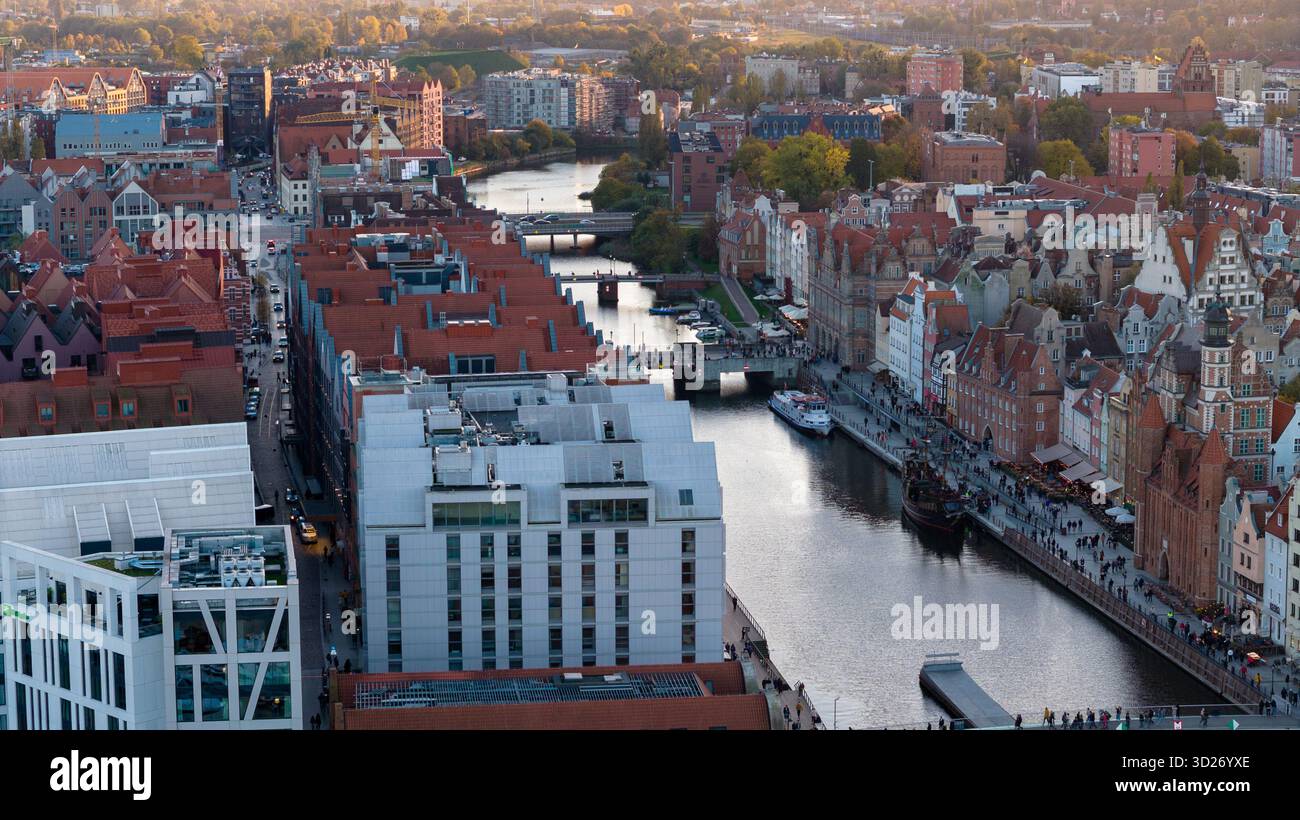 La vue aérienne montre la vieille ville de Gdansk sur la rivière Motlawa avec l'église St Marys, la grue de Gdansk, le front de mer moderne et les bateaux d'excursion en fin d'après-midi Banque D'Images
