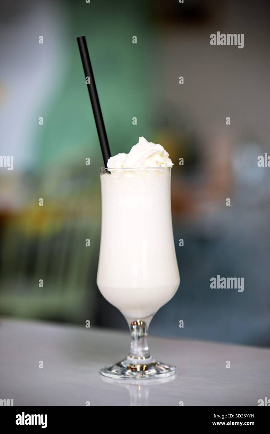 Un verre de lait blanc avec une paille dedans. La paille est noire et le verre est clair Banque D'Images
