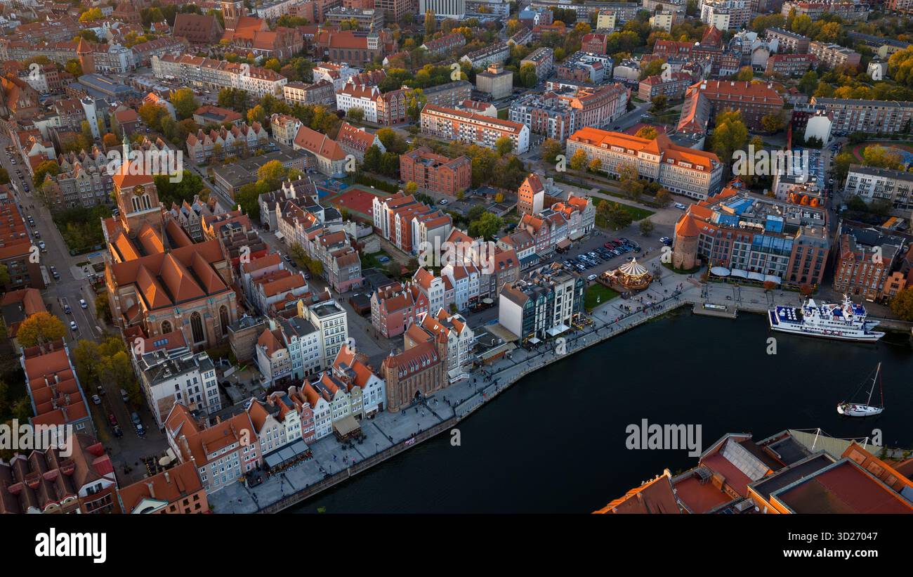 Vue aérienne de la vieille ville de Gdansk en Pologne, l'église Marys s'élève au-dessus des rues pavées, les landes des bateaux d'excursion sur la rivière Motlawa, la lumière chaude jette lon Banque D'Images