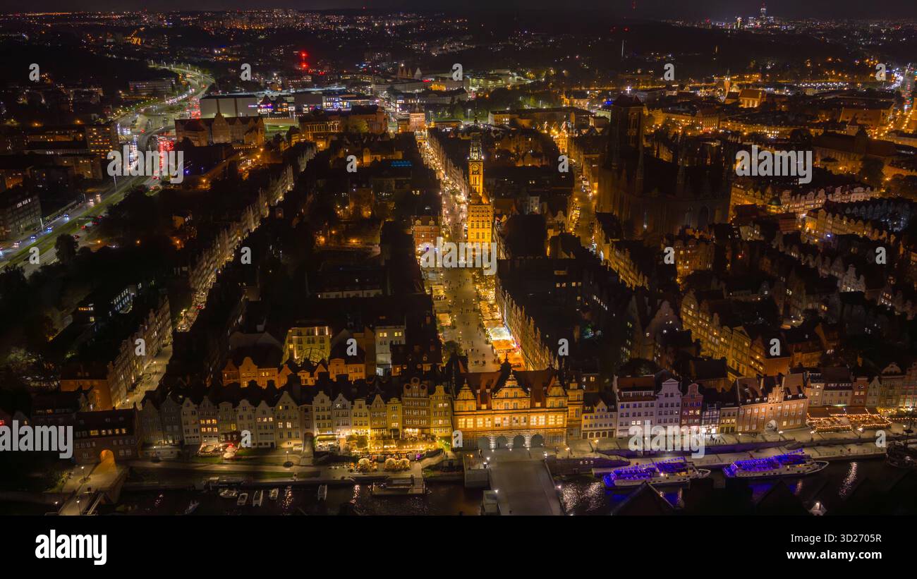 Scène nocturne aérienne montre la vieille ville de Gdansk, la rivière Motlawa, Dlugi Targ, la tour de l'horloge de la mairie principale, l'église Marys, les bateaux d'excursion et la grue médiévale Banque D'Images