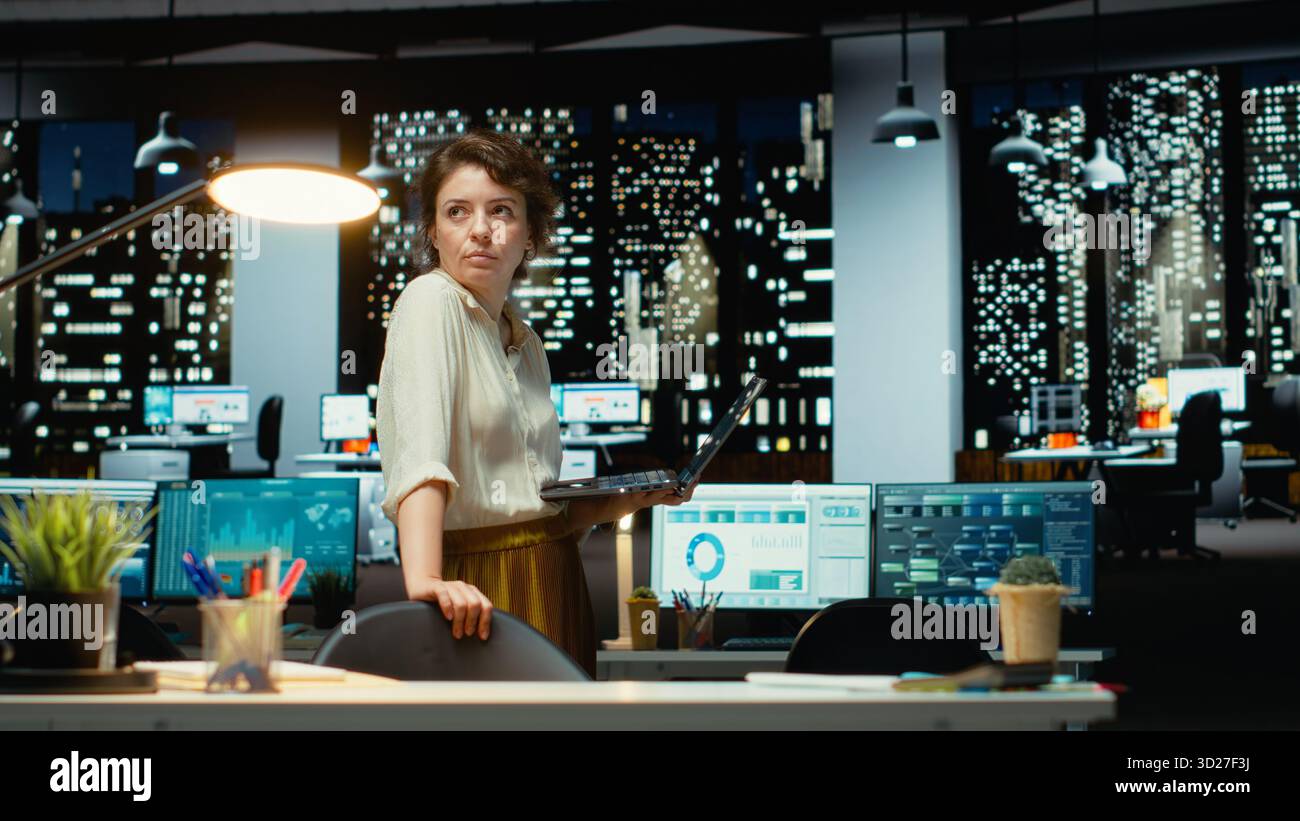 Femme d'affaires la nuit lisant des données financières et des rapports de relecture, debout et prenant des décisions stratégiques pour aider la multinationale à atteindre des cibles ou à renforcer des objectifs. Caméra A. Banque D'Images