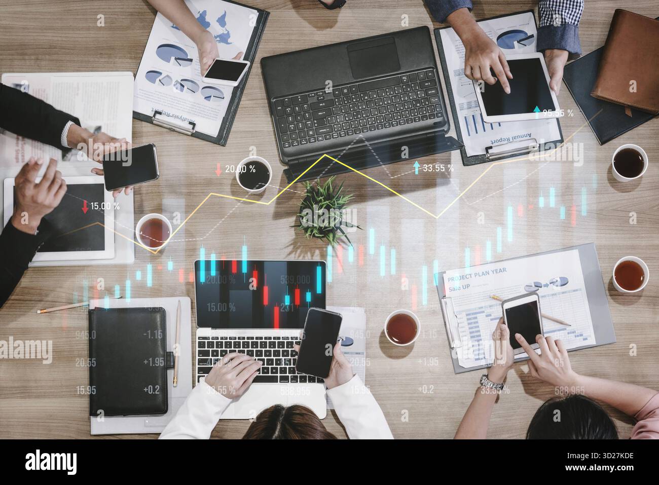 Les professionnels s'engagent dans une analyse financière intense à l'aide d'ordinateurs portables et de smartphones tout en collaborant à une table de bureau moderne, entourée de graphiques et Banque D'Images