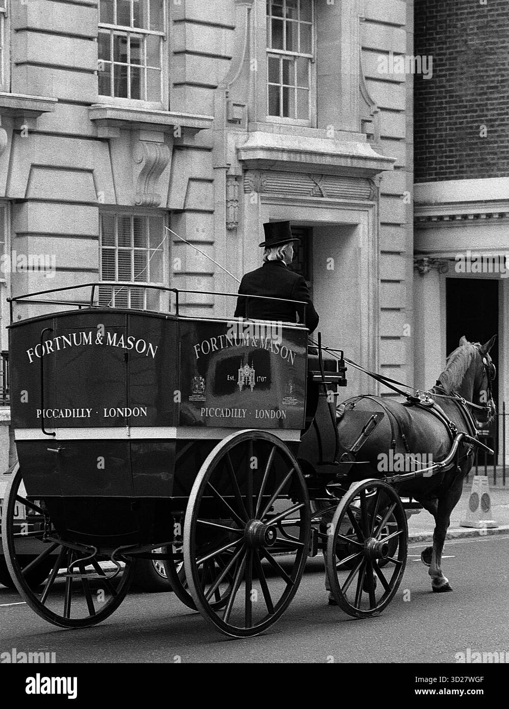 Une scène londonienne classique se déroule comme une charrette tirée par des chevaux, arborant la signalisation historique Fortnum & Mason, navigue sur Piccadilly. Le grand magasin emblématique, un monument de Londres, se dresse fièrement en arrière-plan, mettant en valeur le charme durable et l'élégance intemporelle du patrimoine commercial de la ville. Cette image capture un moment du commerce londonien traditionnel, évoquant un sens de l'histoire et un luxe sur mesure. Banque D'Images