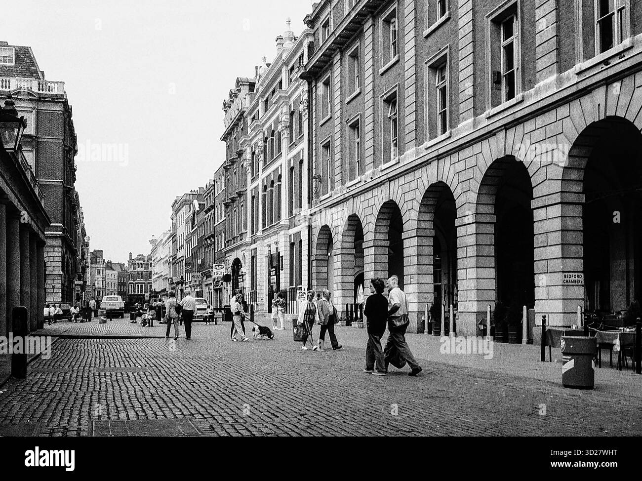 Une scène intemporelle se déroule sur Salisbury Street à Londres, 1986. L'architecture historique de la rue, caractérisée par de grands bâtiments en pierre et d'imposantes arches, témoigne du riche patrimoine de la ville. Les piétons se promènent le long du pavé, créant un sentiment de vie quotidienne au milieu du paysage urbain emblématique. Cette photographie capture un moment de beauté urbaine tranquille, offrant un aperçu du passé de Londres. Banque D'Images