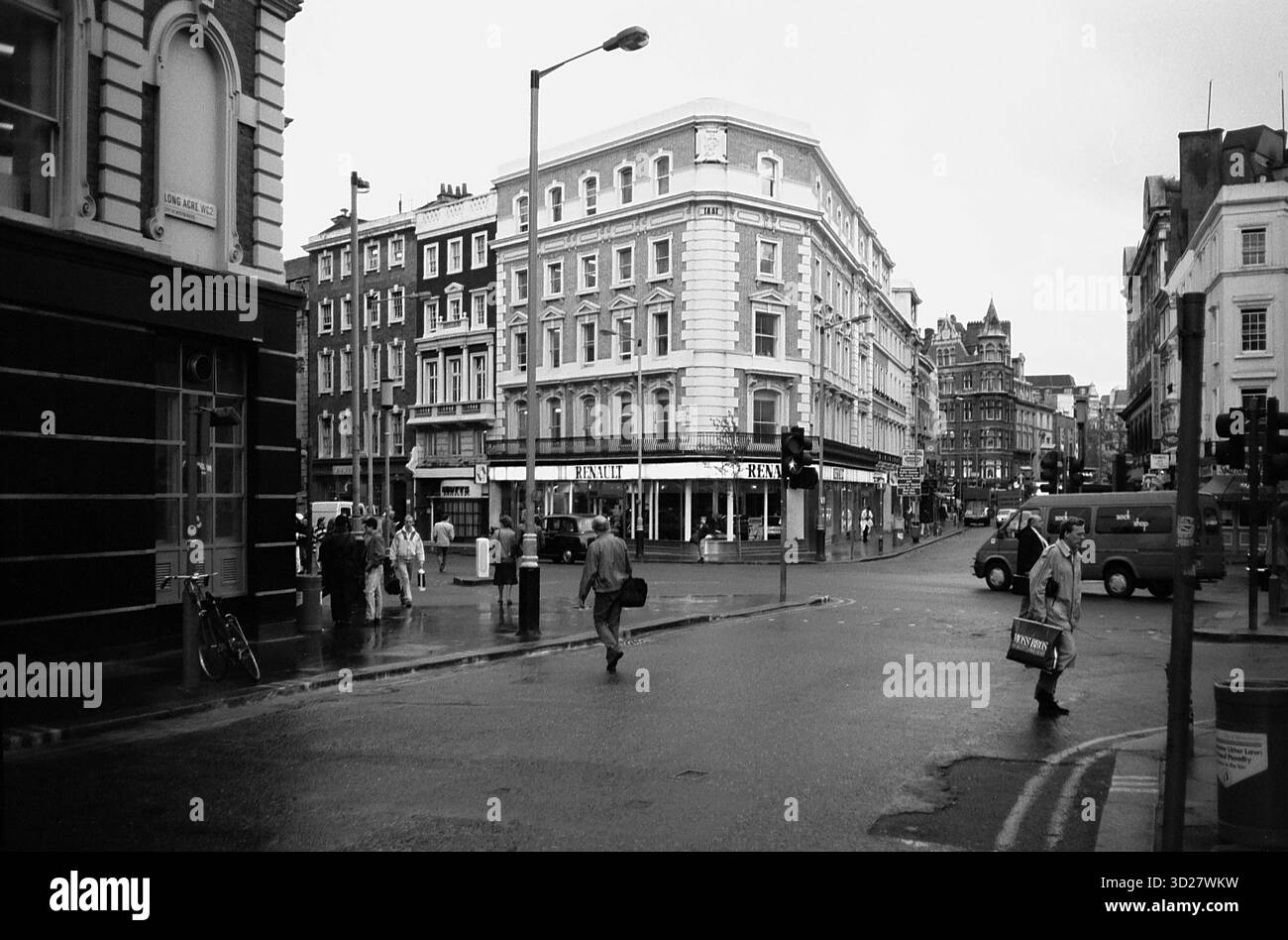Les rues de Londres baignées de pluie révèlent un coin historique, où l'architecture victorienne rencontre l'agitation de la vie urbaine moderne. L’emblématique skyline du Royaume-Uni est visible au loin, ajoutant au charme intemporel de cette capitale britannique. Banque D'Images