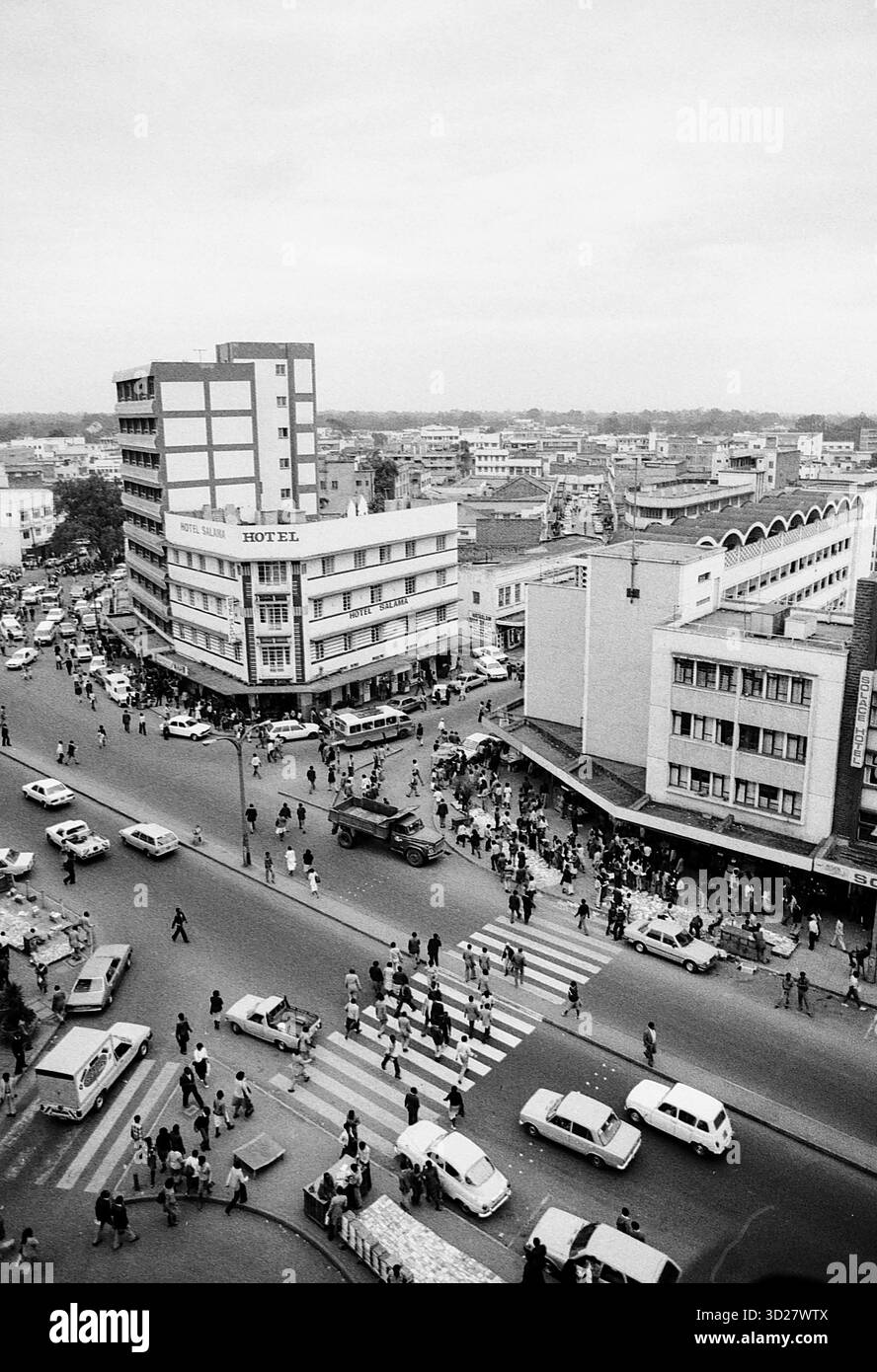 Les rues animées de Nairobi pulsent avec la vie dans cette photographie emblématique des années 1960. L’emblématique bâtiment KENVA domine l’horizon, témoignant du patrimoine architectural de la ville. L'image capture un instantané vibrant de la vie quotidienne, avec des piétons naviguant sur l'intersection achalandée et des véhicules remplissant la route. Cette vue historique offre un aperçu du passé de Nairobi, une ville qui évolue rapidement vers une métropole moderne. Banque D'Images