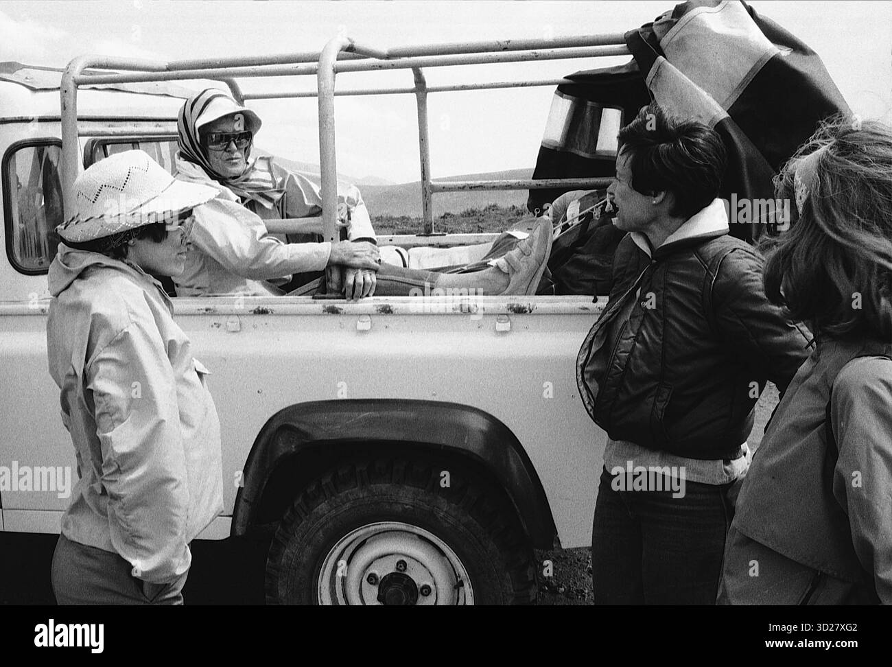 Les touristes observent un guide de safari dans le cratère de Ngorongoro, en Tanzanie. Le groupe est rassemblé autour d'un véhicule, probablement une jeep, tandis que le guide montre un point de repère ou la faune dans la vaste caldeira. Banque D'Images