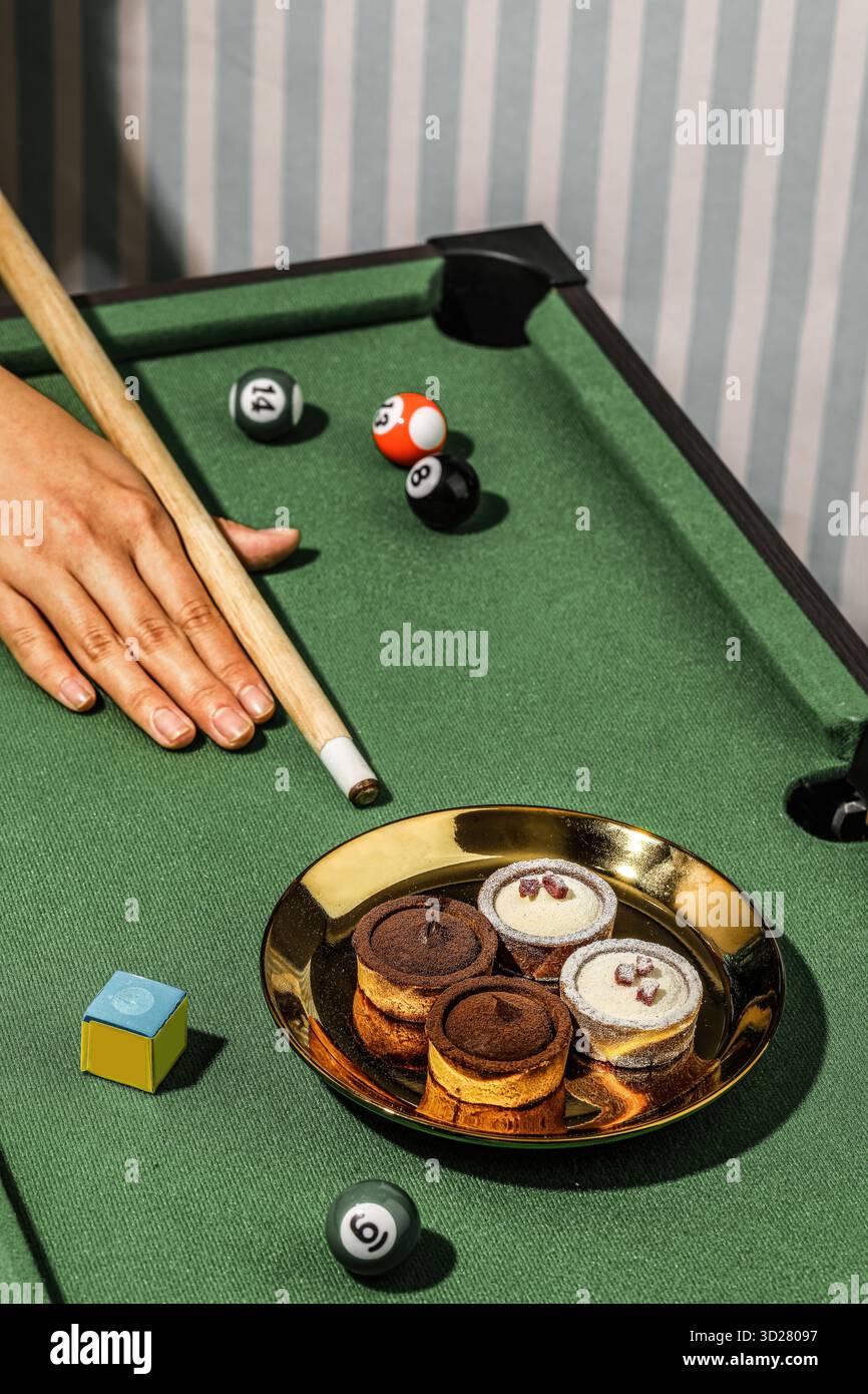 Photographie de table de billard avec mini tartes sur une plaque d'or avec Pool Cue et balles dans le cadre du casino Banque D'Images