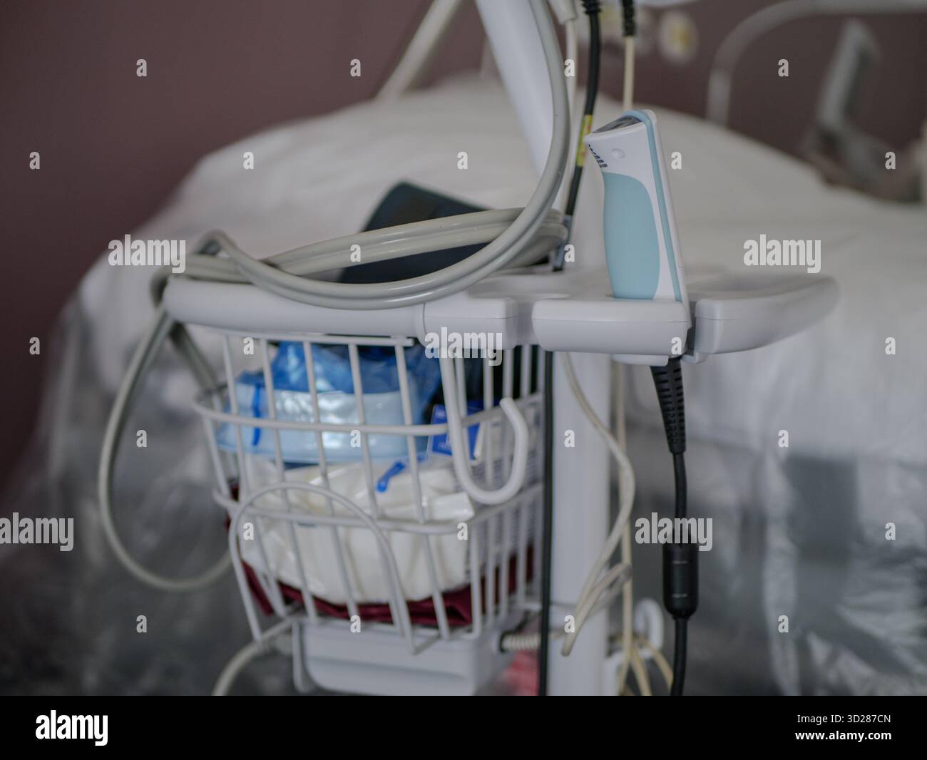 Gros plan sur un chariot d'hôpital rempli de fournitures médicales, de câbles et d'outils de surveillance à côté d'un lit de patient dans une salle clinique. L'image montre la santé réelle Banque D'Images