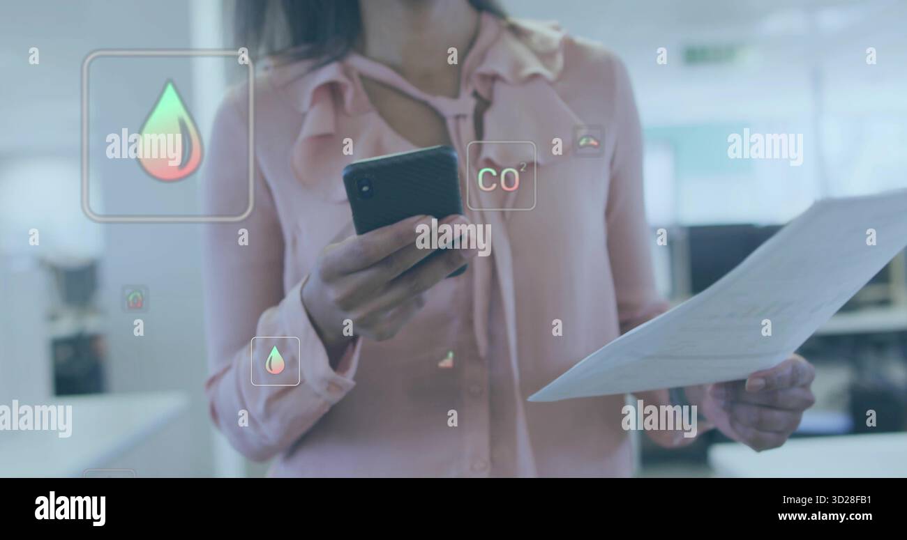 Travailleuse de bureau analysant la superposition dans un bureau ouvert, avec smartphone, document et icônes CO2 Banque D'Images
