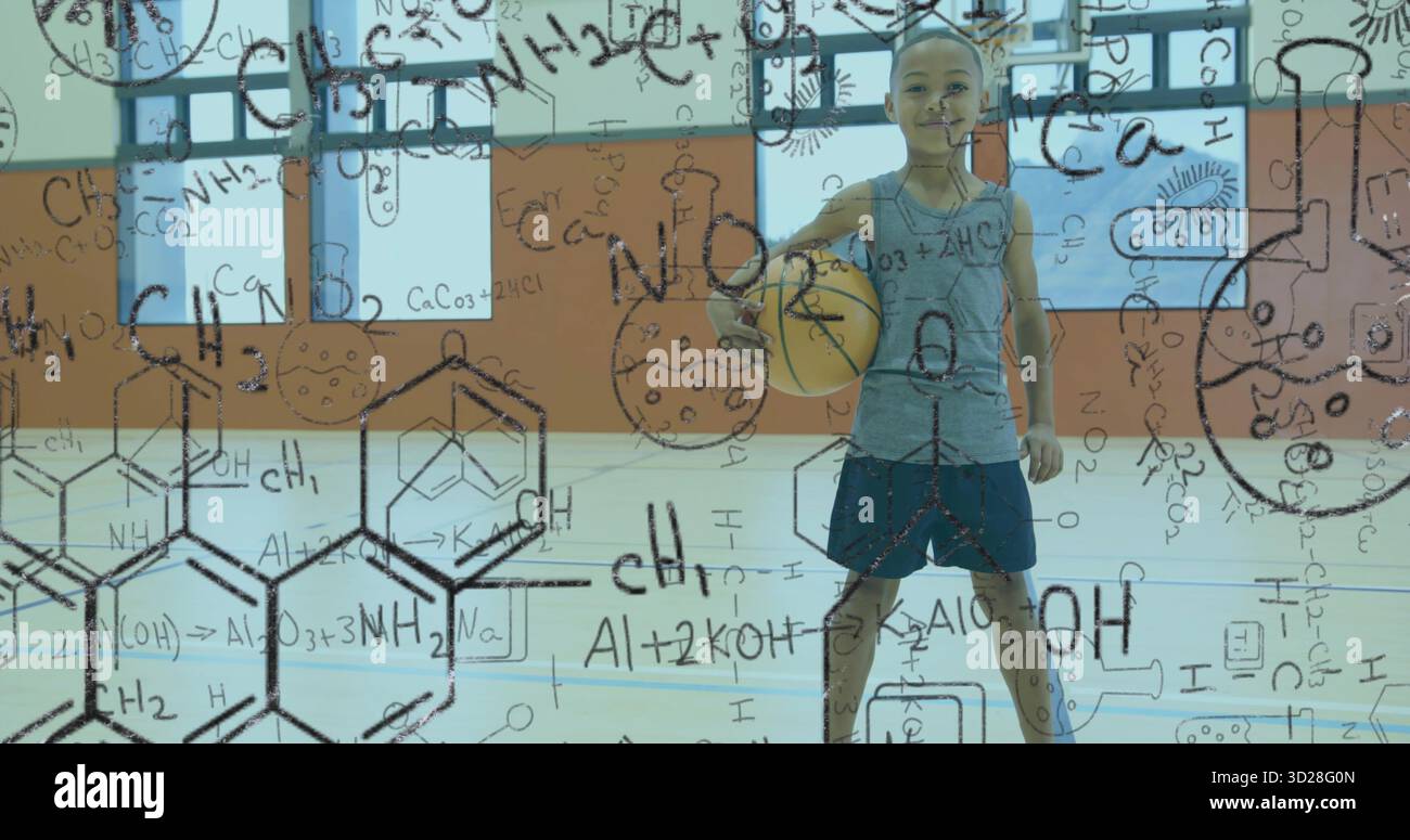 Garçon d'âge scolaire debout en vêtements de sport tenant le basket-ball à l'intérieur de la salle de gym avec revêtement sur le thème de la science Banque D'Images