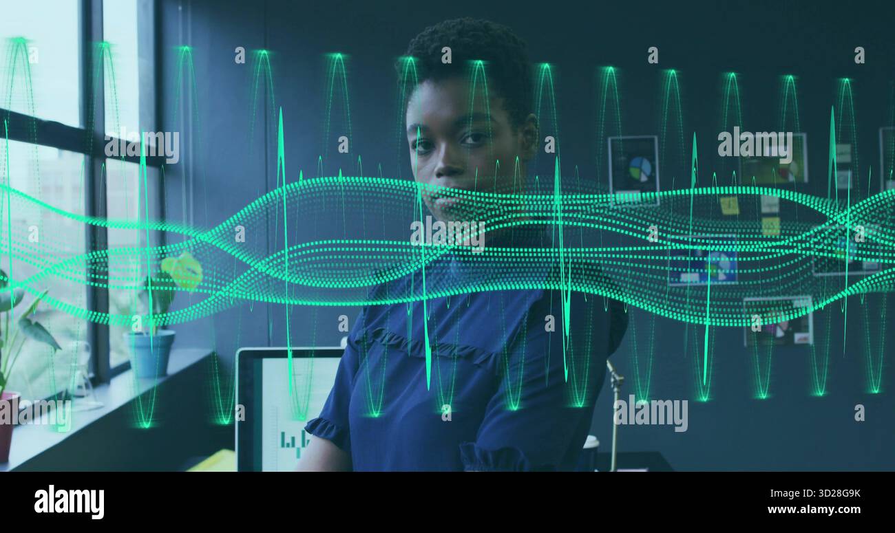 Examen des graphiques Tech femme professionnelle portant chemisier bleu au bureau dans le bureau, avec des formes d'onde Banque D'Images