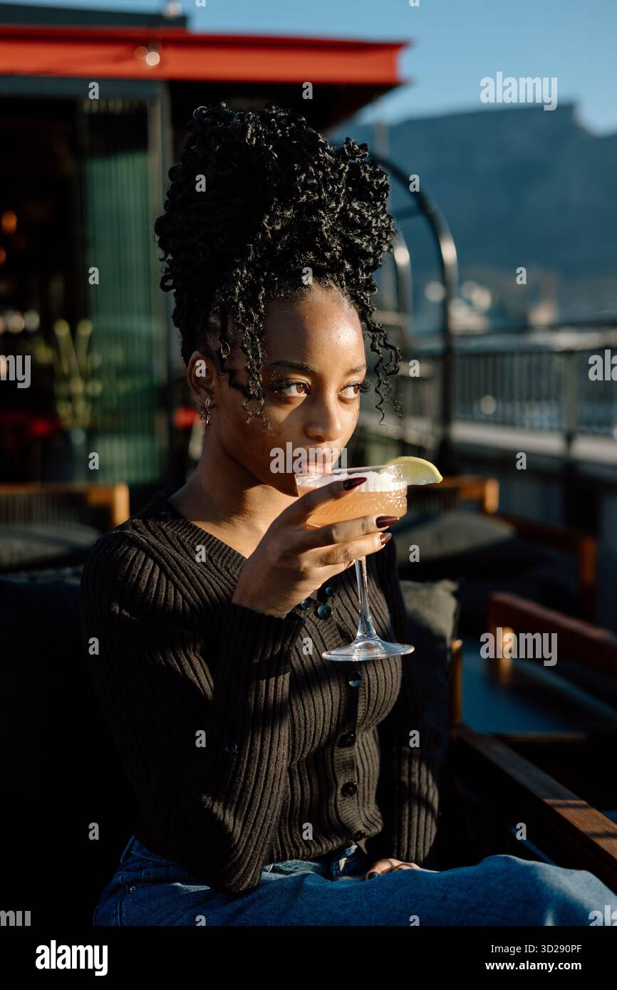 Jeune femme buvant un cocktail à l'extérieur Banque D'Images