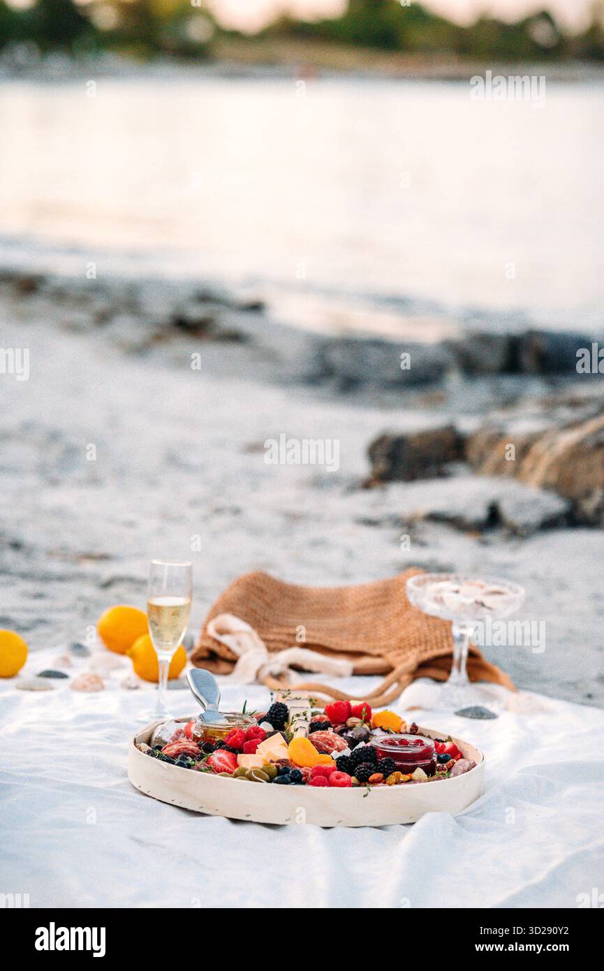 Pique-nique charcuterie et champagne sur la plage au coucher du soleil Banque D'Images