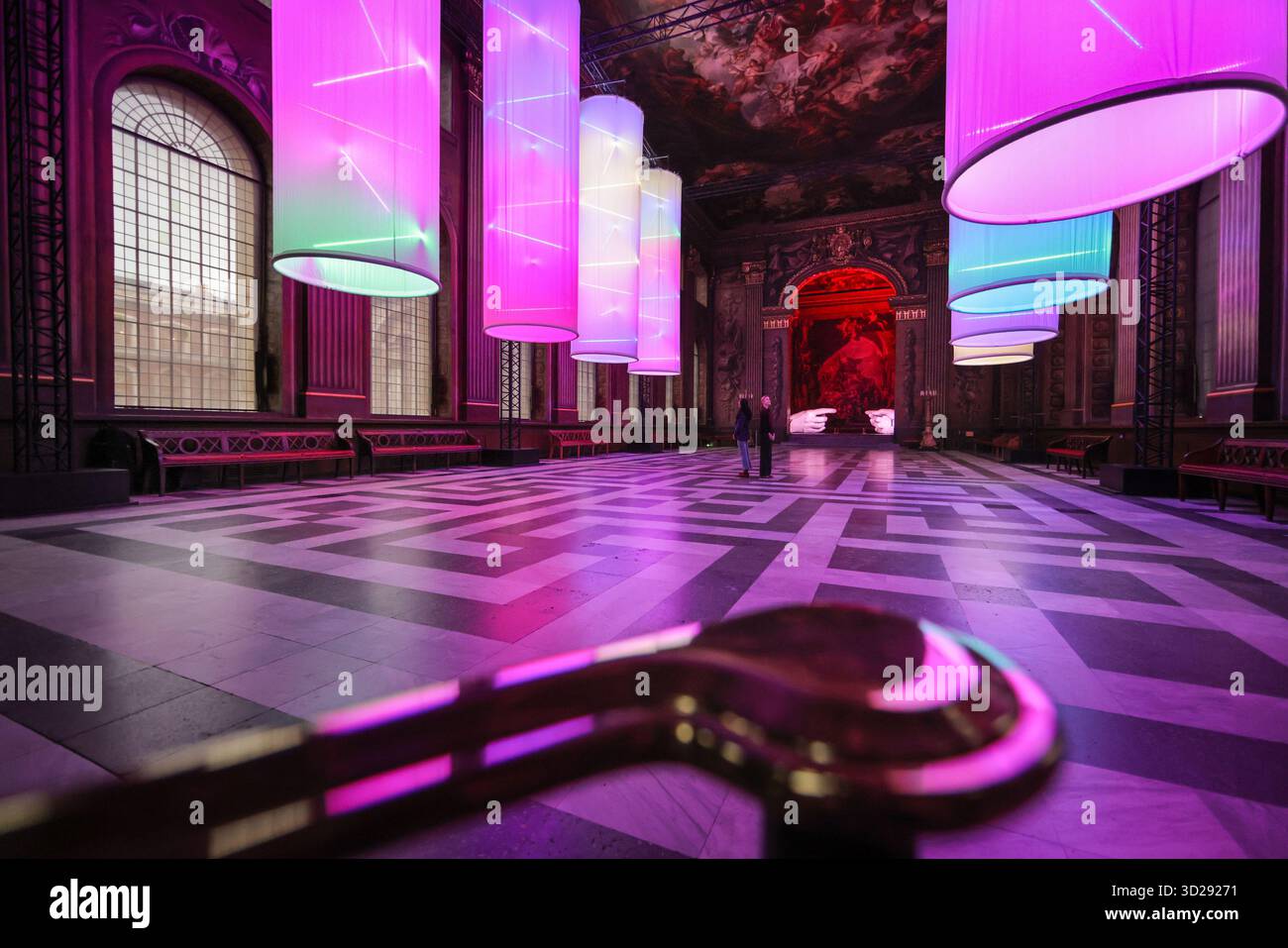 Londres, Royaume-Uni. 31 octobre 2025. Personnel avec les installations de Peter Walker 'Connection' and Identity' dans le Painted Hall de l'Old Royal Naval College, Greenwich. « Identity » montre huit colonnes suspendues illuminées, évoquant les structures de l'ADN, et « Connection » est une réinterprétation moderne de la création d'Adam de Michel-Ange, remplaçant les mains traditionnellement masculines par des moulages de mains féminines. Crédit : Imageplotter/Alamy Live News Banque D'Images
