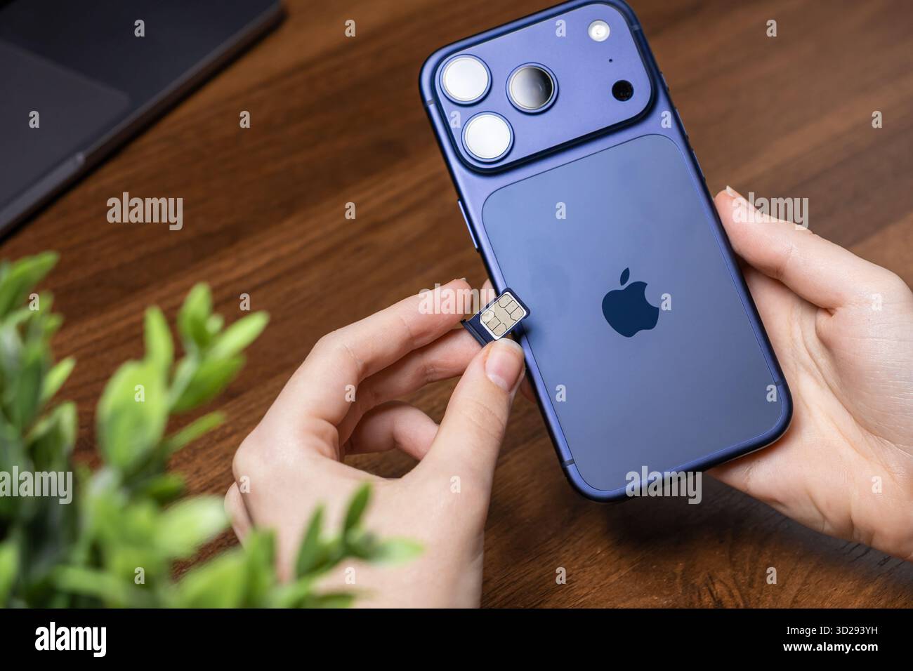 Poznan, Pologne - 16 octobre 2025 : les mains de l'utilisateur insèrent méticuleusement une carte nano SIM dans l'iPhone 17 Pro violet, établissant des données mobiles cruciales an Banque D'Images