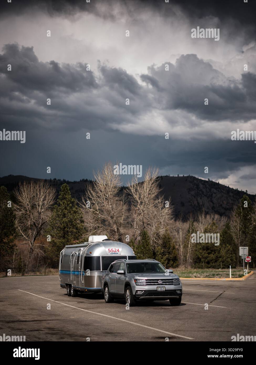 Remorque de voyage Airstream et véhicule de remorquage à un arrêt de repos inter-états avec ciel sombre dans le Montana, États-Unis, Amérique du Nord. Banque D'Images