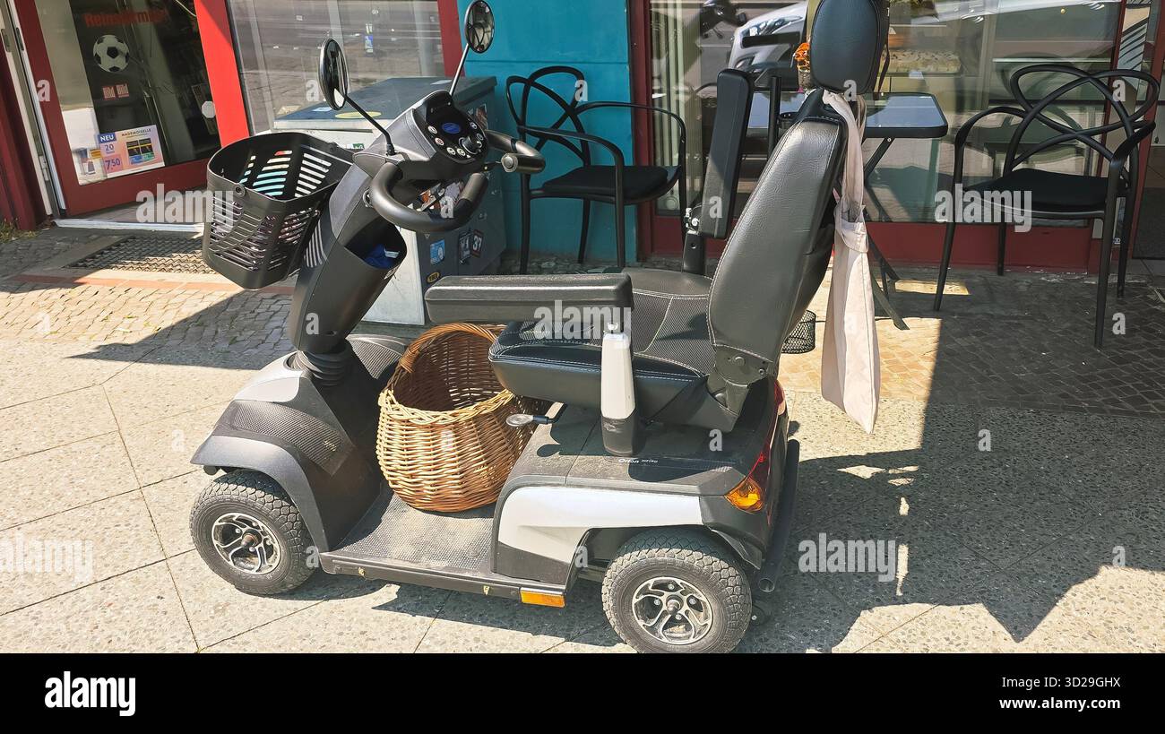 Berlin, Allemagne - 17 juin 2025 : scooter de mobilité est garé devant un café, avec un panier pour la commodité du shopping. Banque D'Images