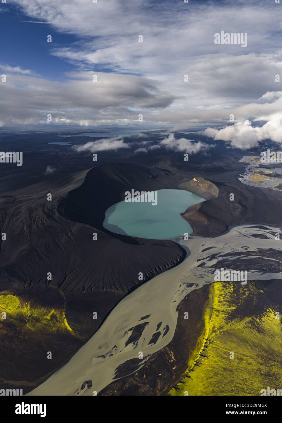 Vue aérienne du lac turquoise niché dans la caldeira volcanique noire et dure, embrassée par la mousse verte vibrante et la rivière qui coule, Highlands of Ice Banque D'Images