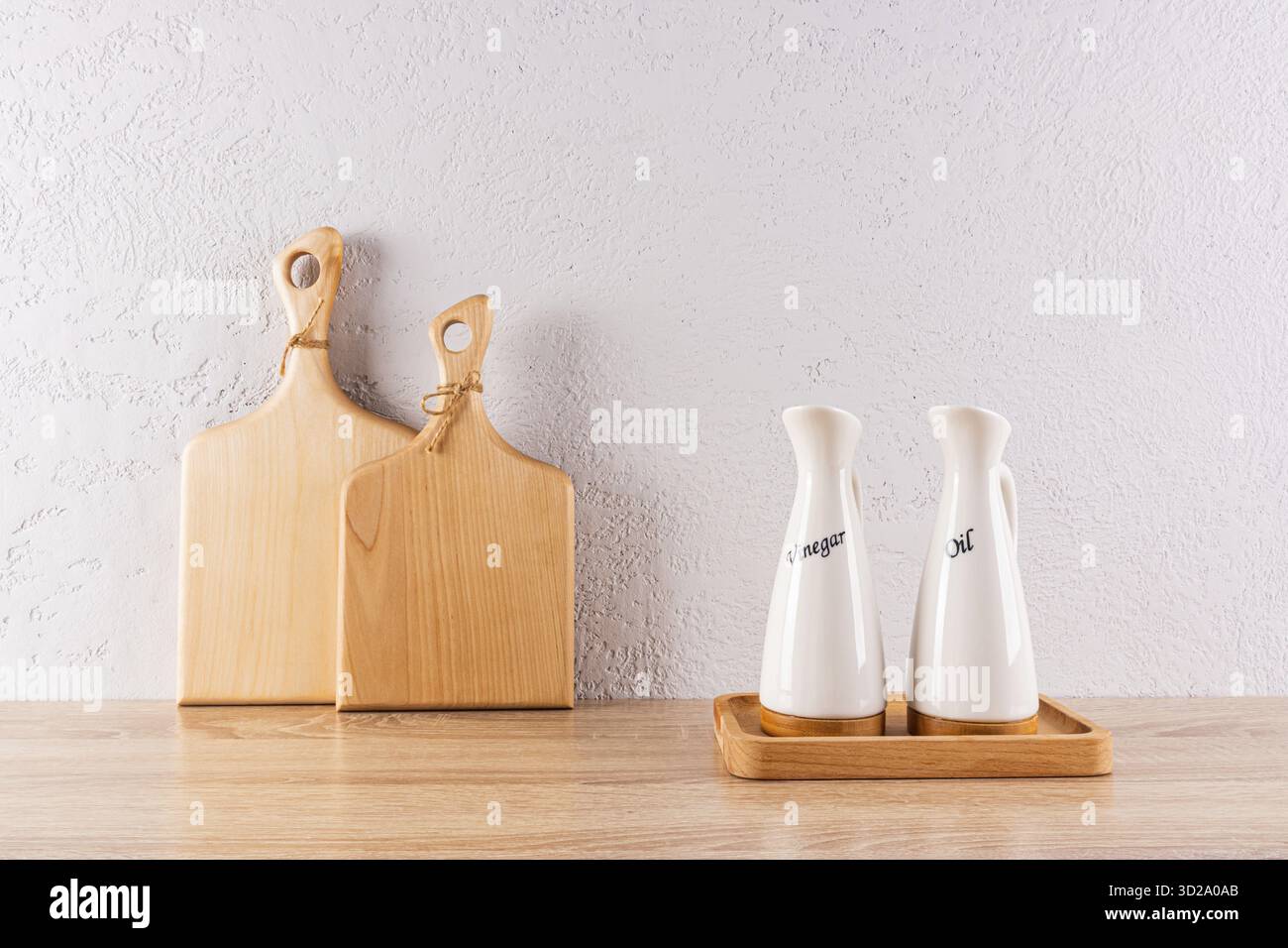 Fond de cuisine dans un style minimaliste. deux planches de bois à découper et deux bouteilles d'huile spéciales en céramique sur un plateau. Paroi en relief. Vue de face Banque D'Images