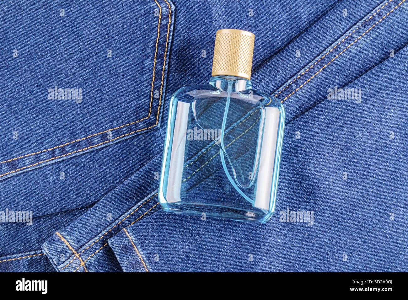Bouteille transparente avec liquide pour hommes de parfum bleu, lotion faciale, eau de toilette sur fond bleu de tissu denim. vue de dessus. Une maquette de bouteille vierge Banque D'Images